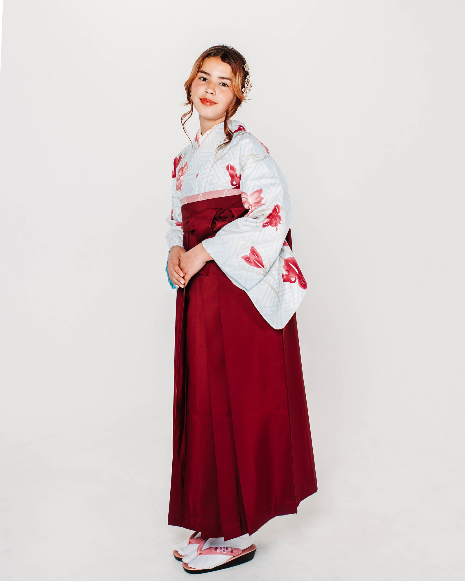 Full-length portrait of a girl wearing a light-blue kimono with red floral designs and a deep red hakama for graduation | 卒業式 水色の着物 赤い花柄 えんじ袴 女の子 全身ポートレート