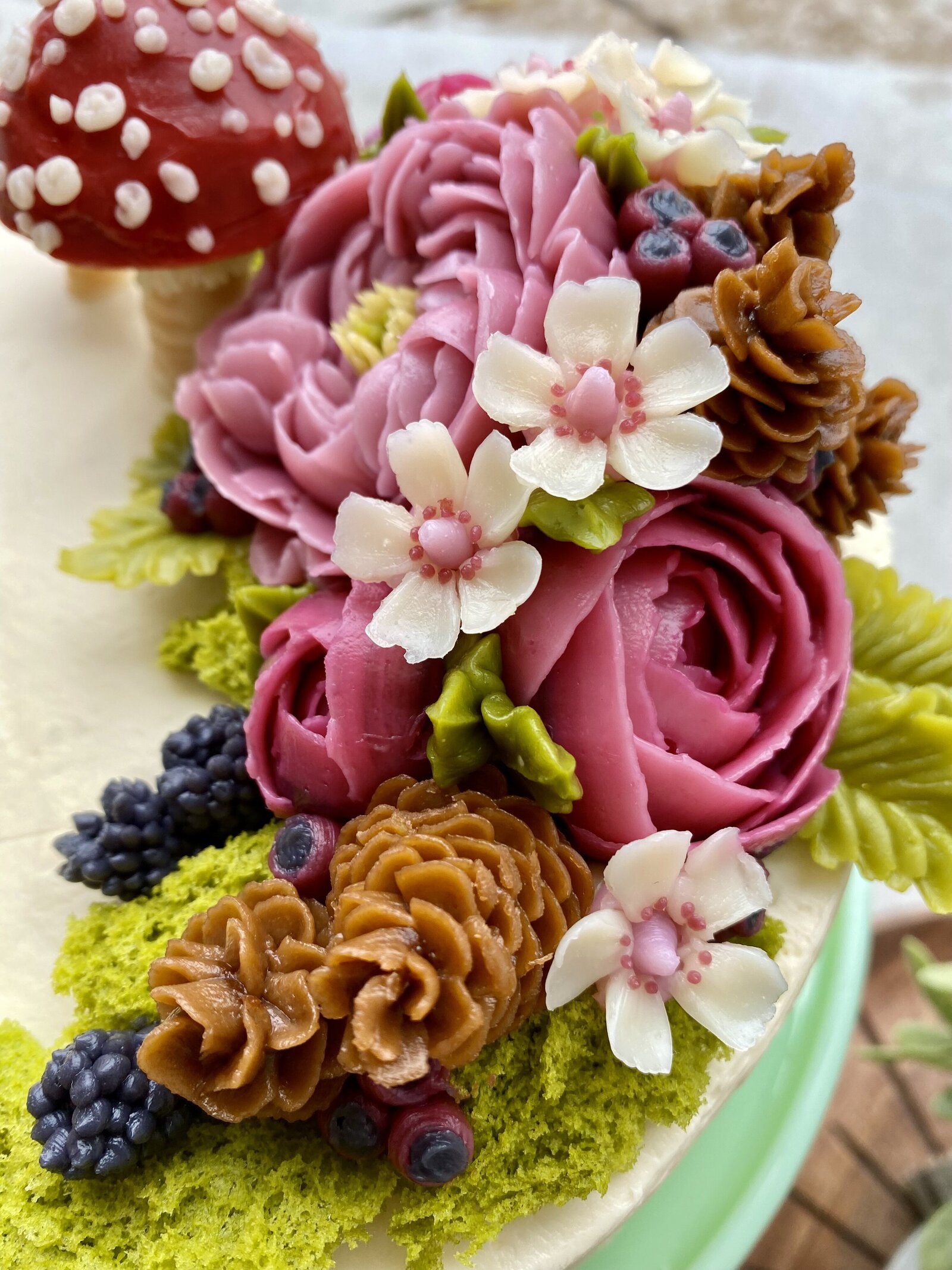 Close up of buttercream flowers and pine cones
