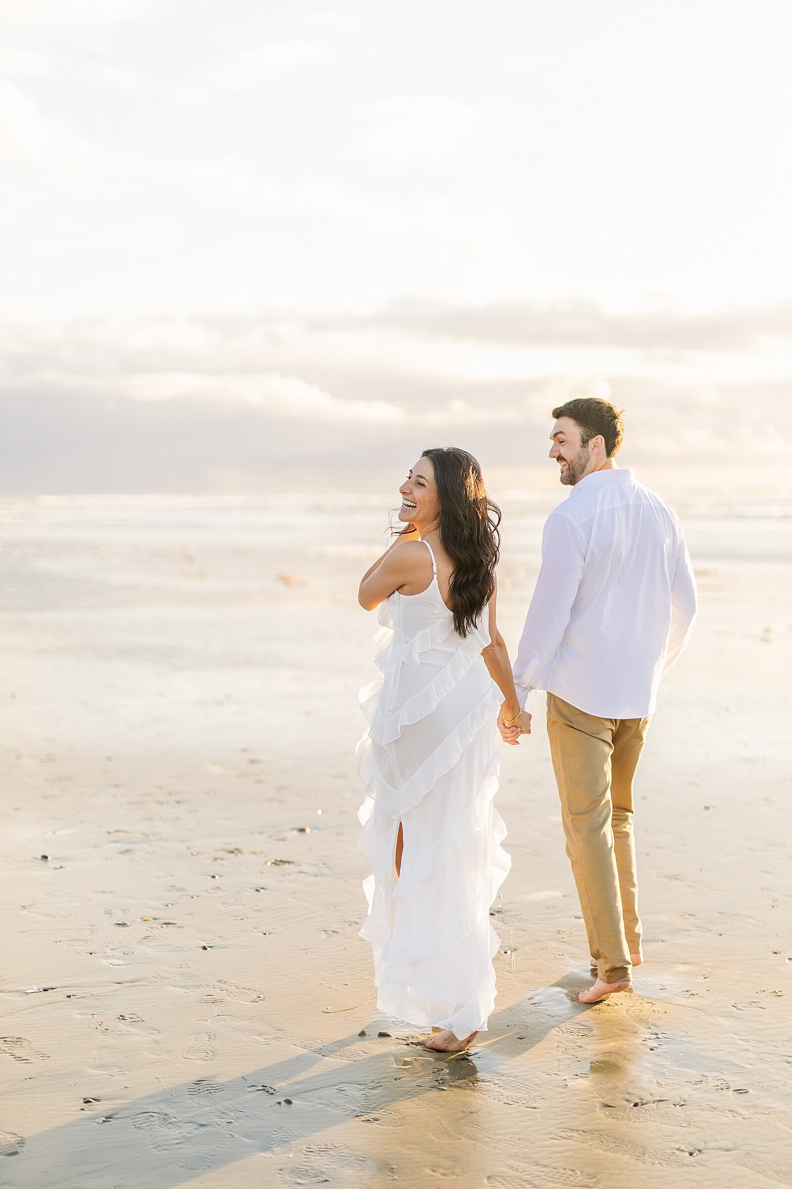 Engaged couple laughing at Del Mar Beach during sunset.