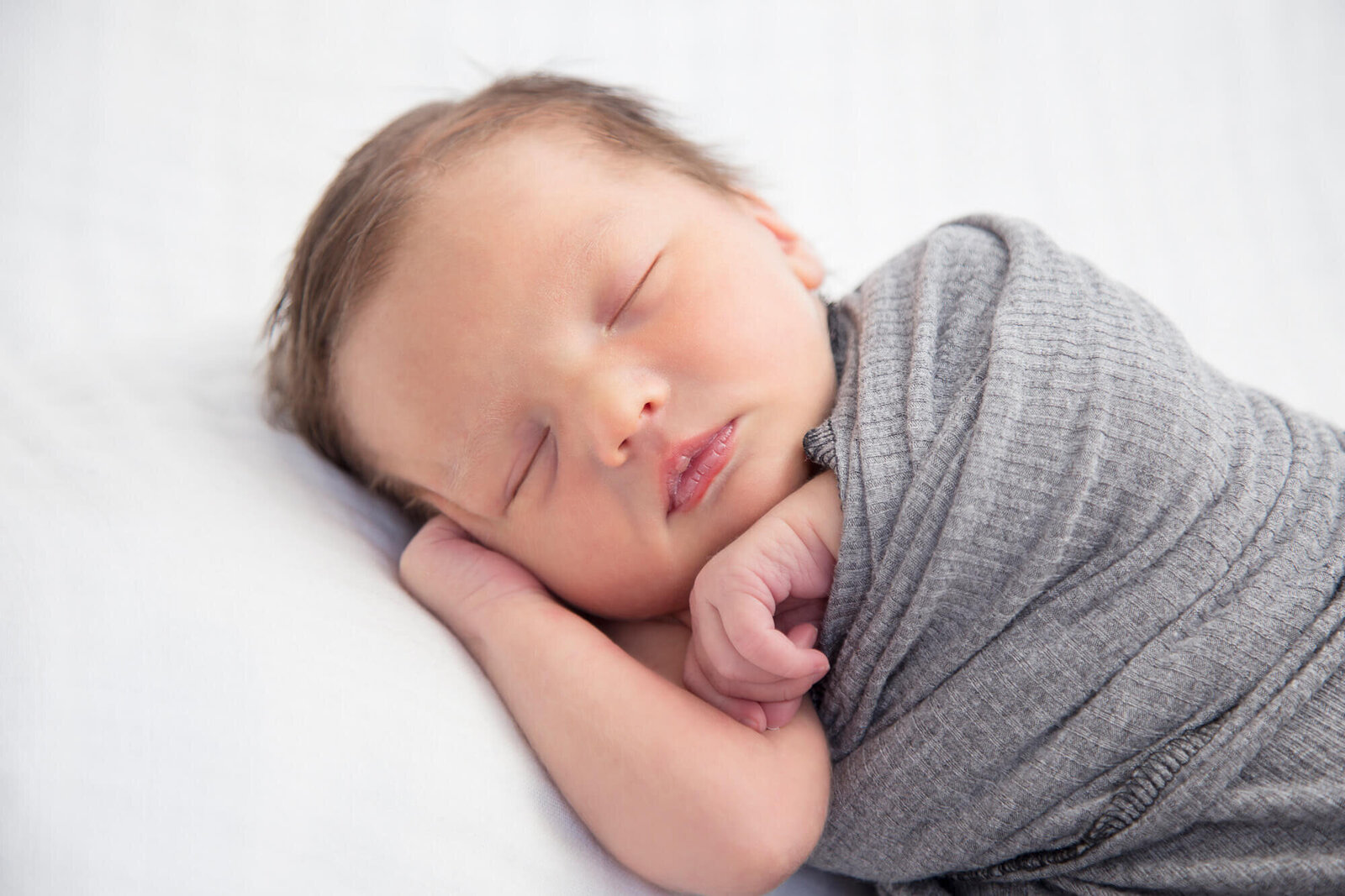 newborn baby wrapped cozy in a gray swaddle blanket