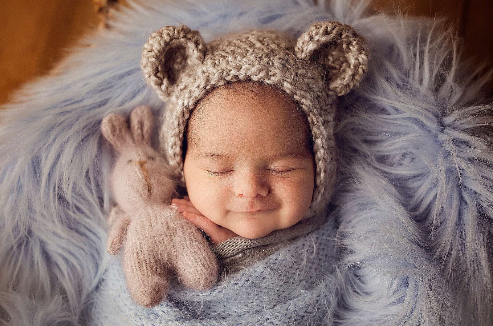 An adorable baby in a bear hat and blue blanket, beautifully photographed by Bia Schaefer in an Orlando newborn session.