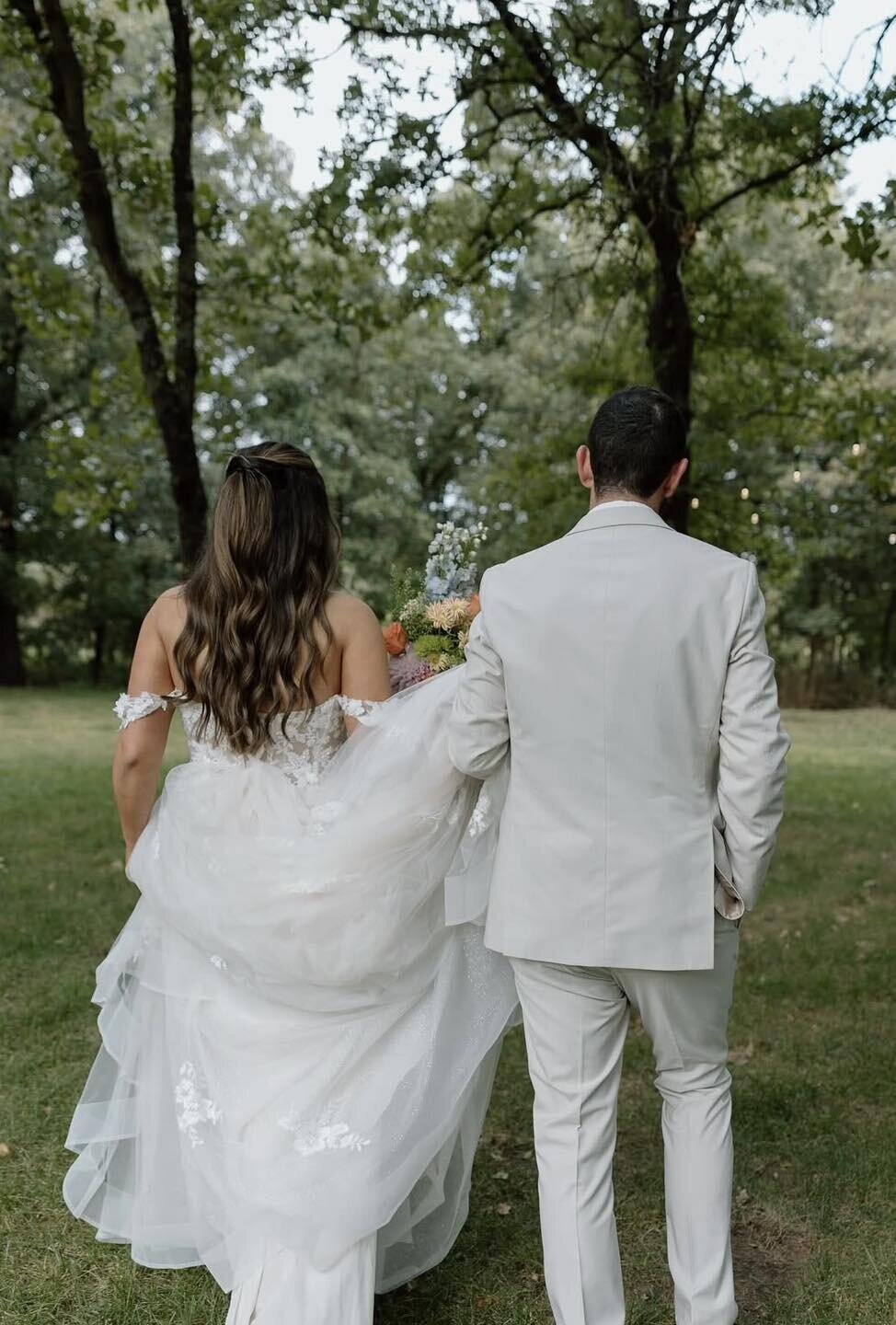 Bride and groom walking together outdoors in matching light-colored wedding attire