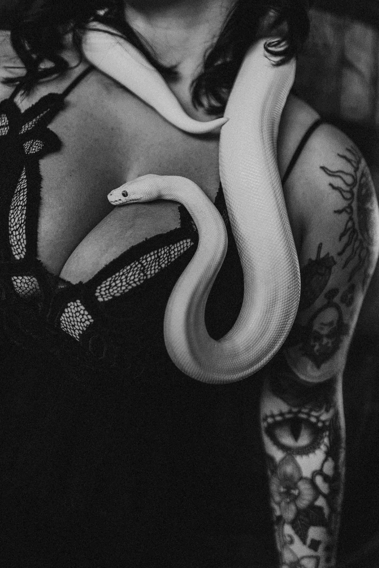 woman in a black lingerie with her white snake on her chest