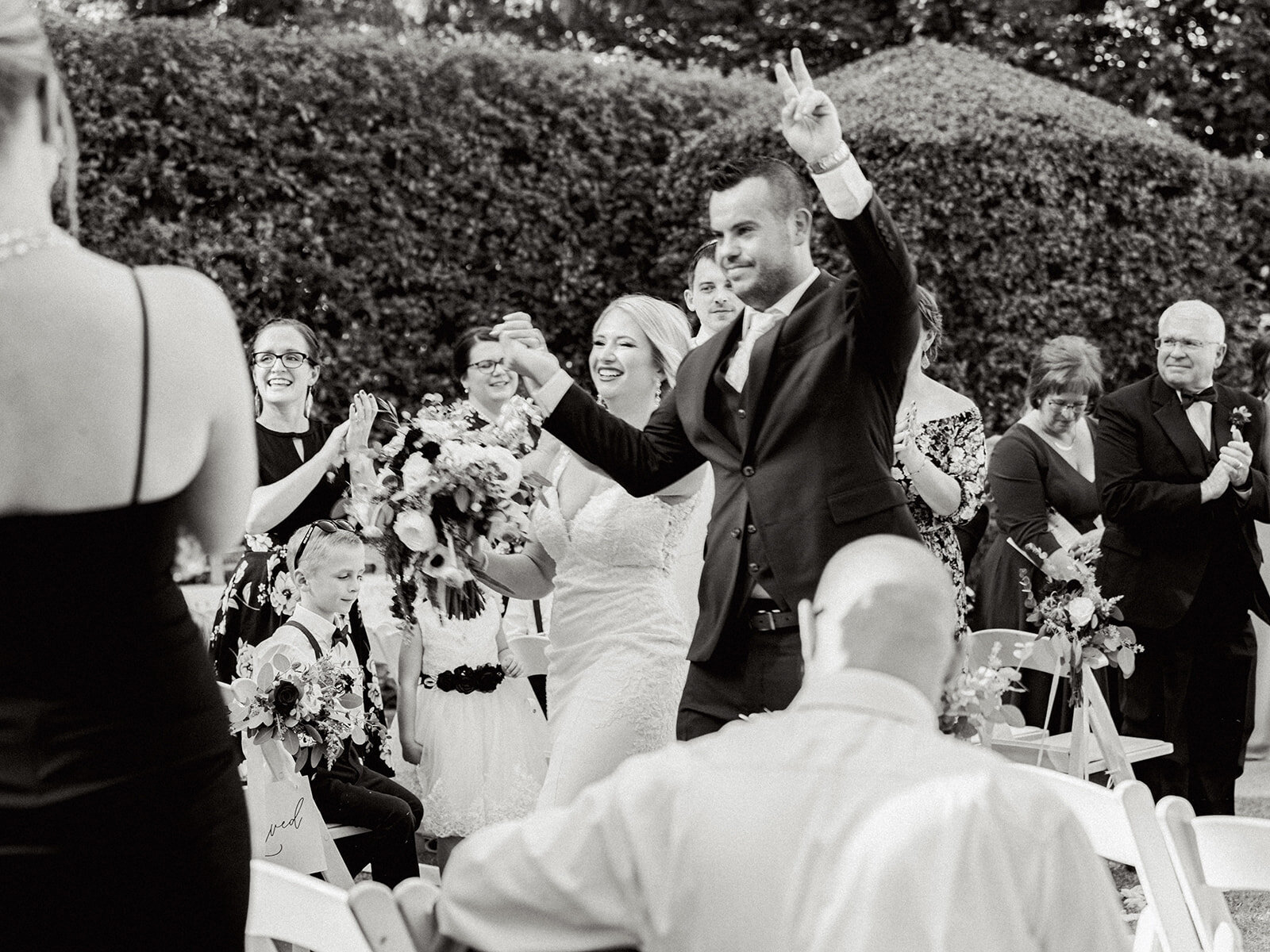 groom holding up the peace sign and holding hands with the bride at the reception