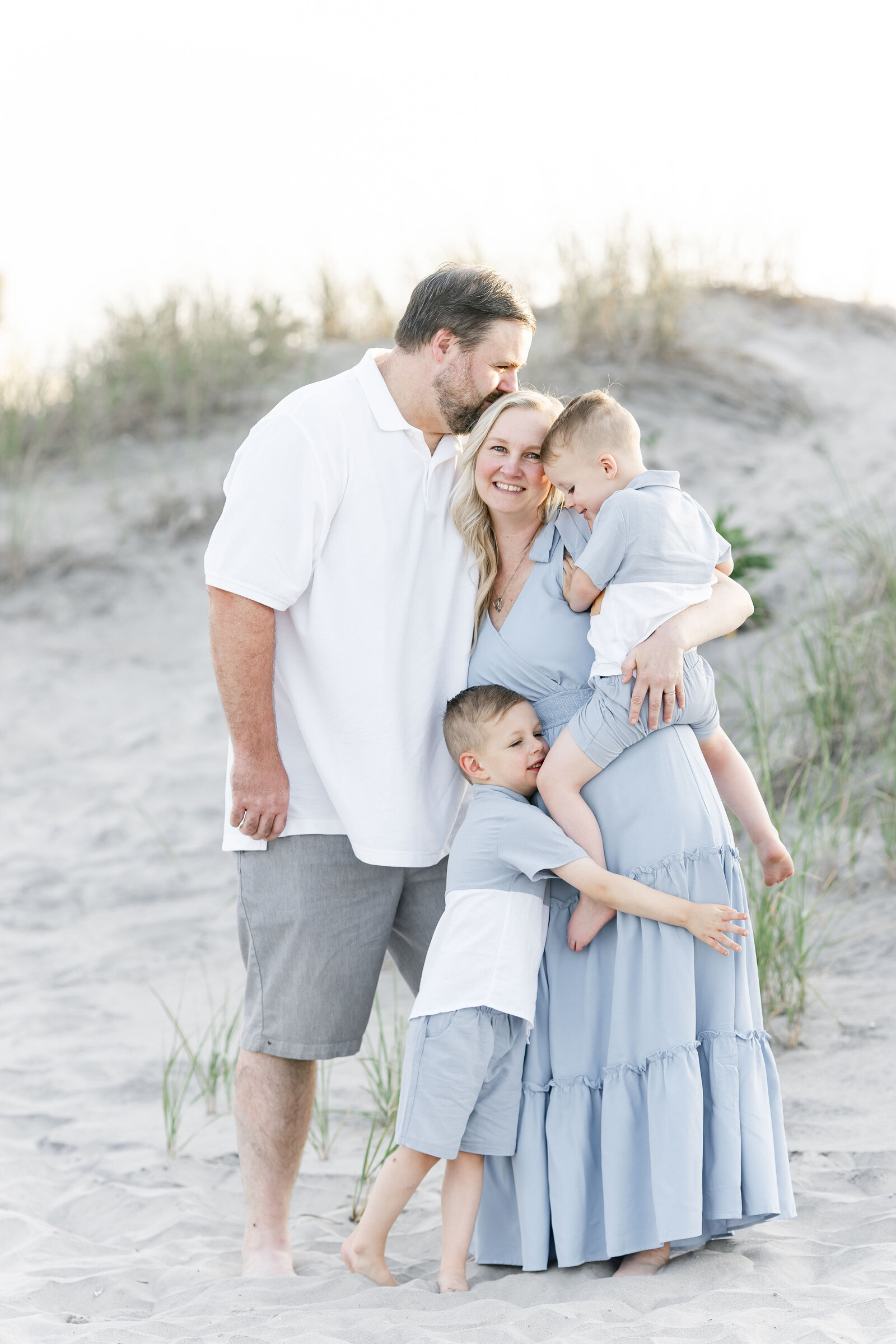 family of four standing on ocean city beach photographed by new jersey family photographer