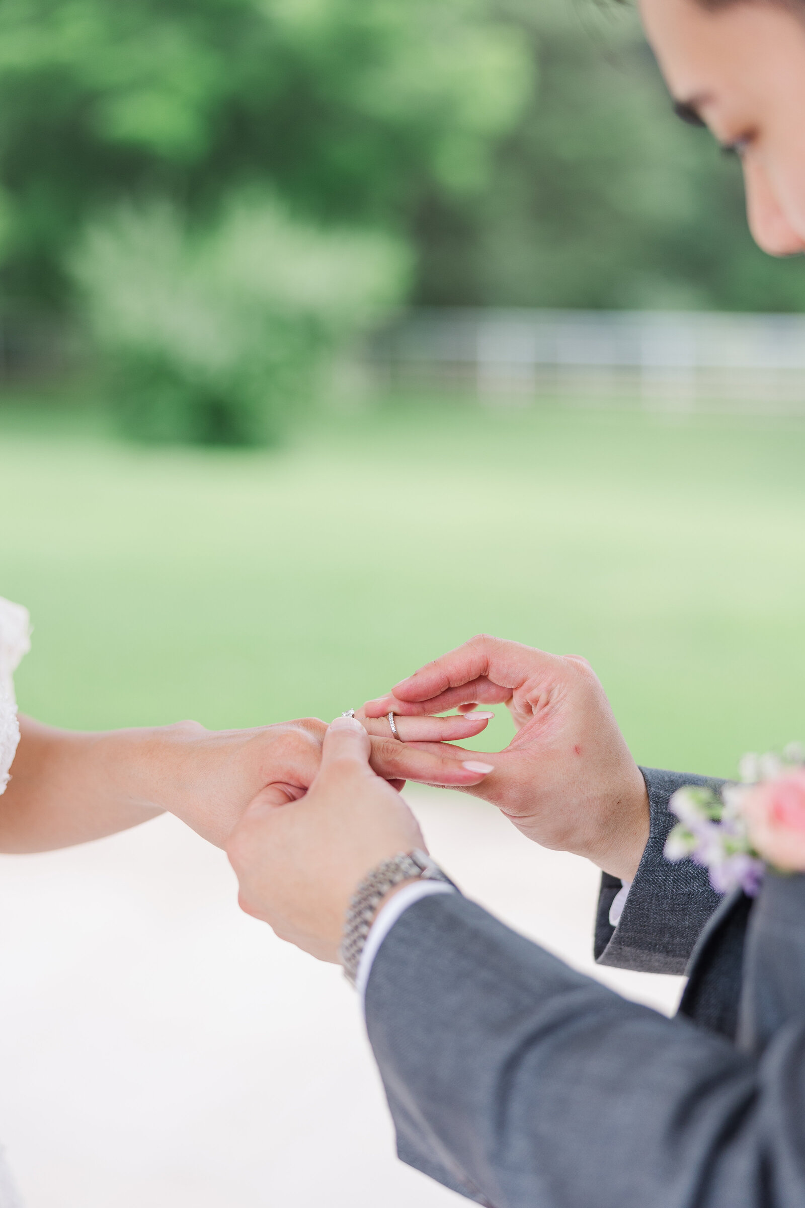 Groom putting ring on bride's finger during wedding ceremony
