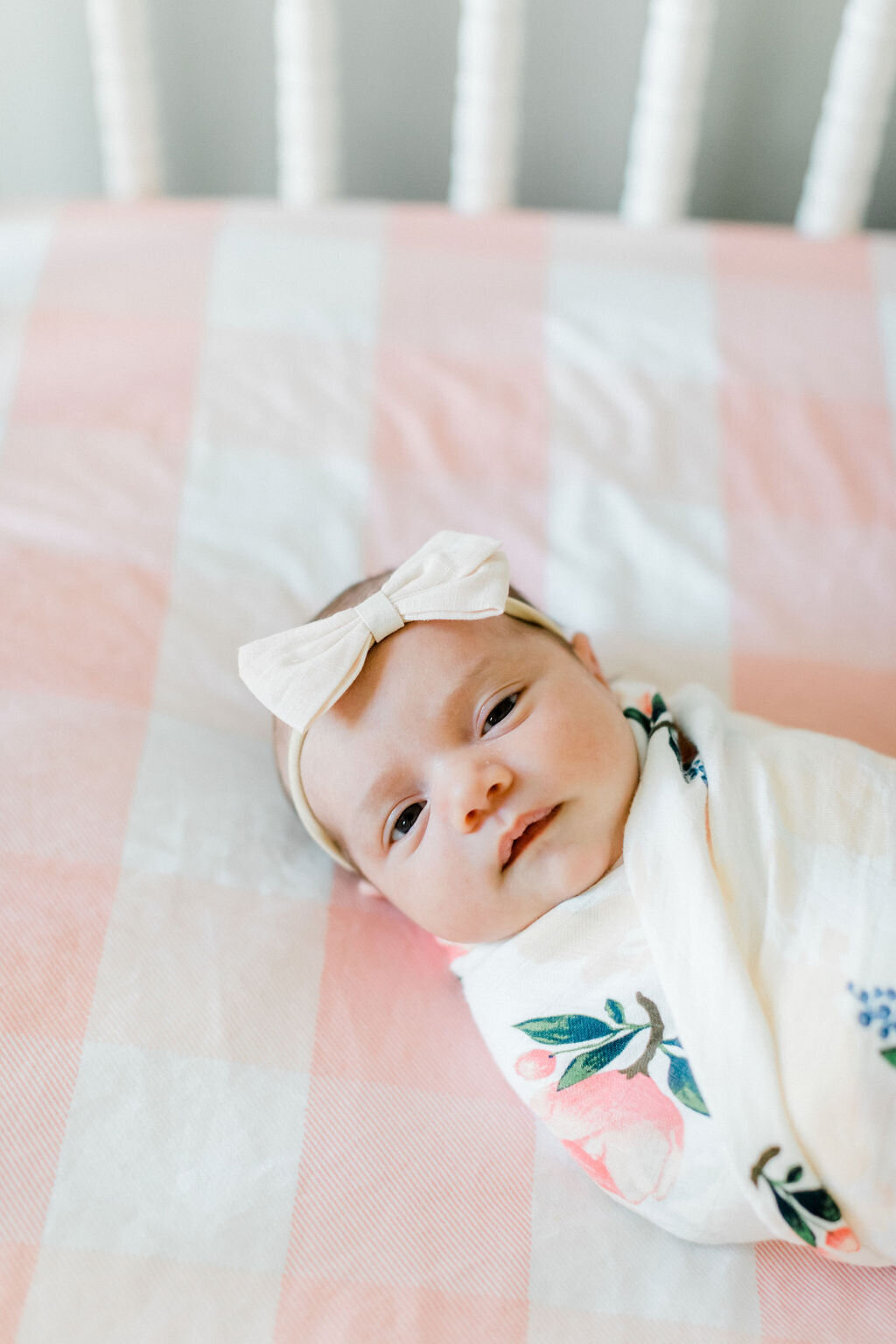 Portrait of a newborn girl swaddled in her crib during a lifestyle newborn session in Richmond, Virginia