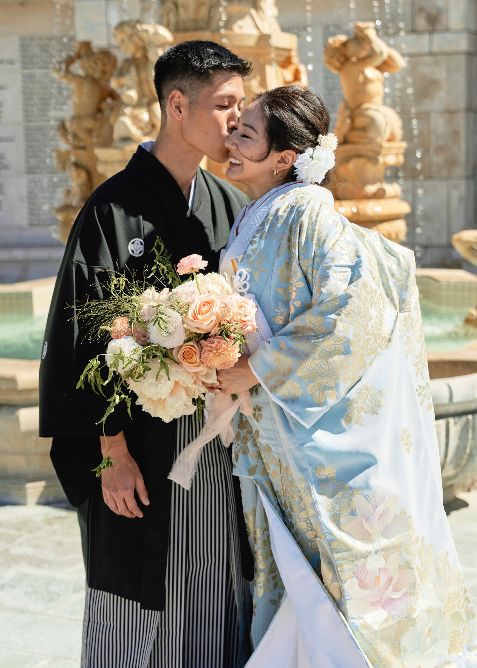 Groom kisses bride in pale blue iro-uchikake kimono during an Orange County kimono rental wedding shoot, available for kimono rental |
オレンジカウンティーの噴水で青い打掛の着物レンタル花嫁にキスする新郎