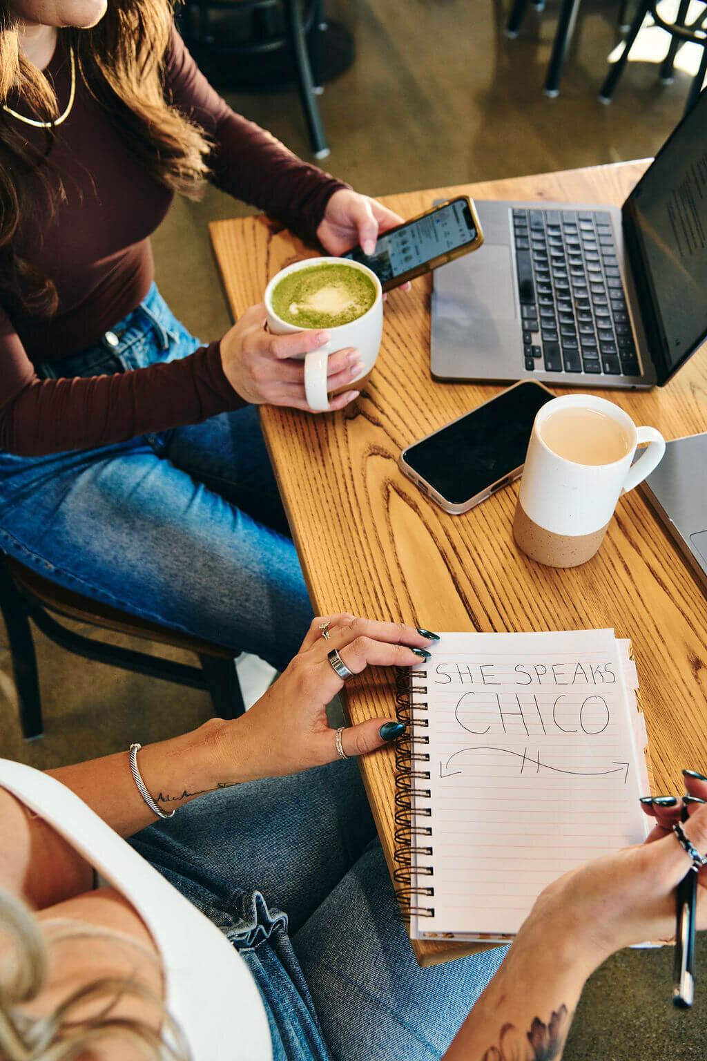 two girls sitting on a couch with mugs on the table