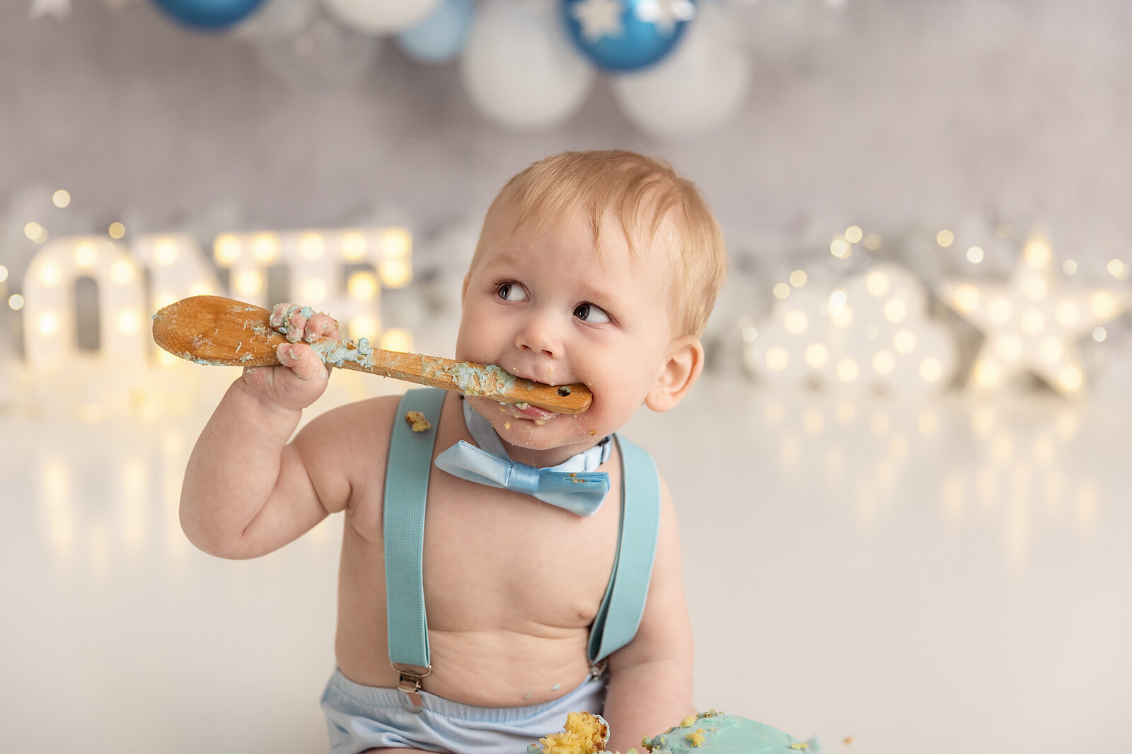 baby boy eating cake off wooden spoon by milestone photographer new philadelphia