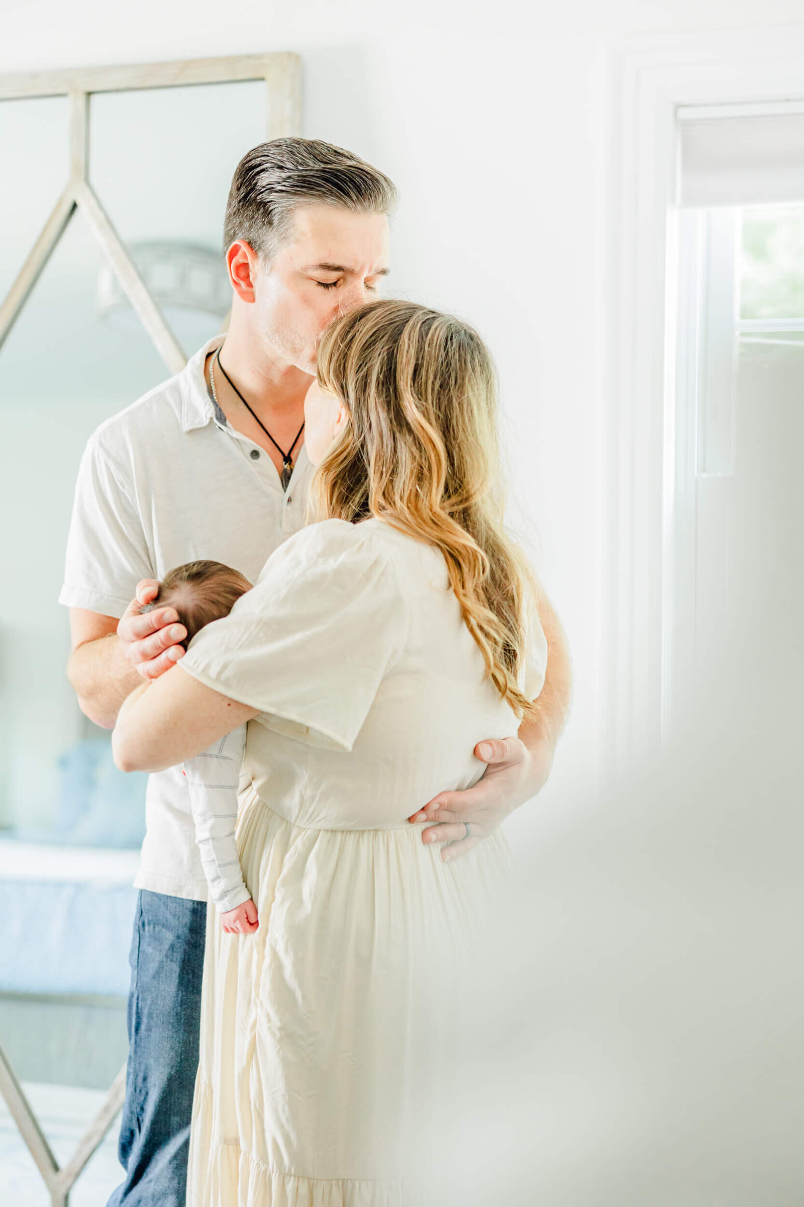 Dad gives mom a kiss while she holds their newborn