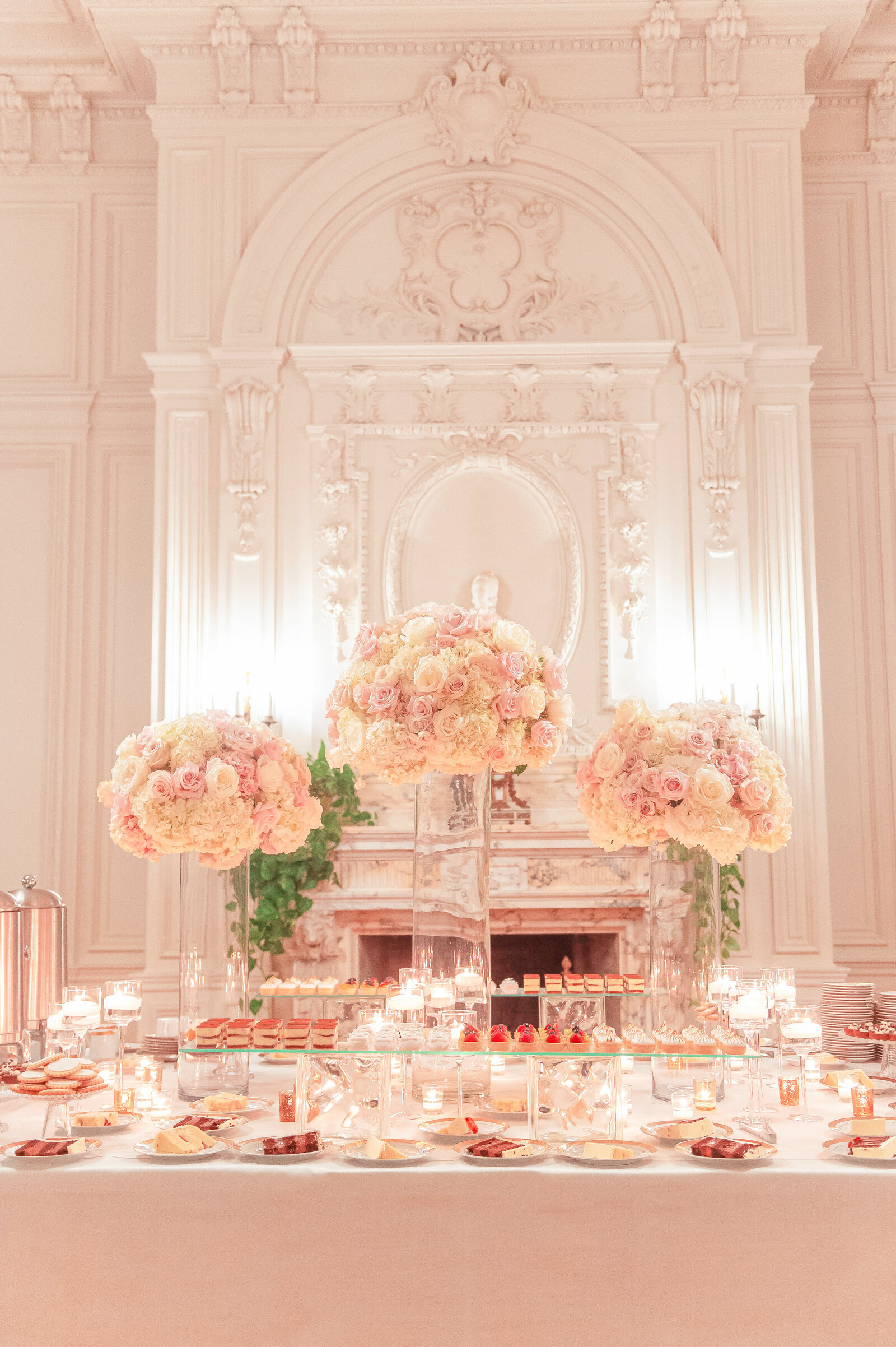 Wedding reception table with candles and large pink floral centerpieces