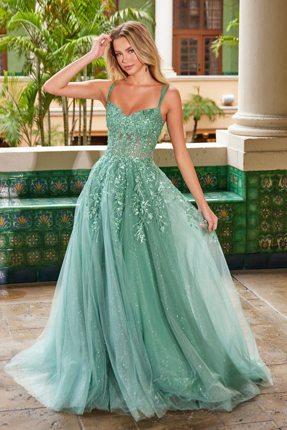 Woman wearing a sparkly mint-green ball gown with floral appliqué bodice