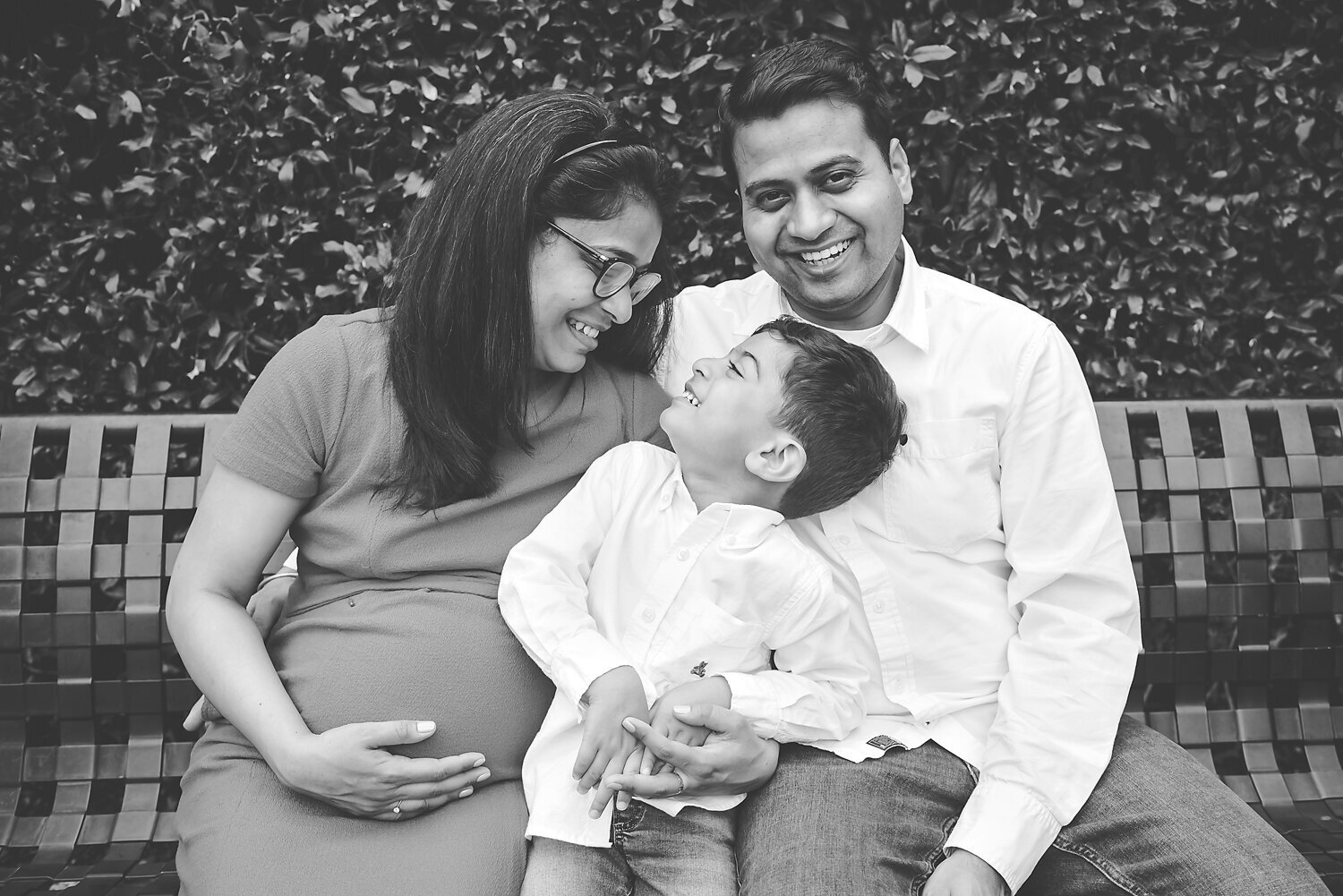 Black and white image of a family laughing and having fun at a maternity session in Dallas, TX.