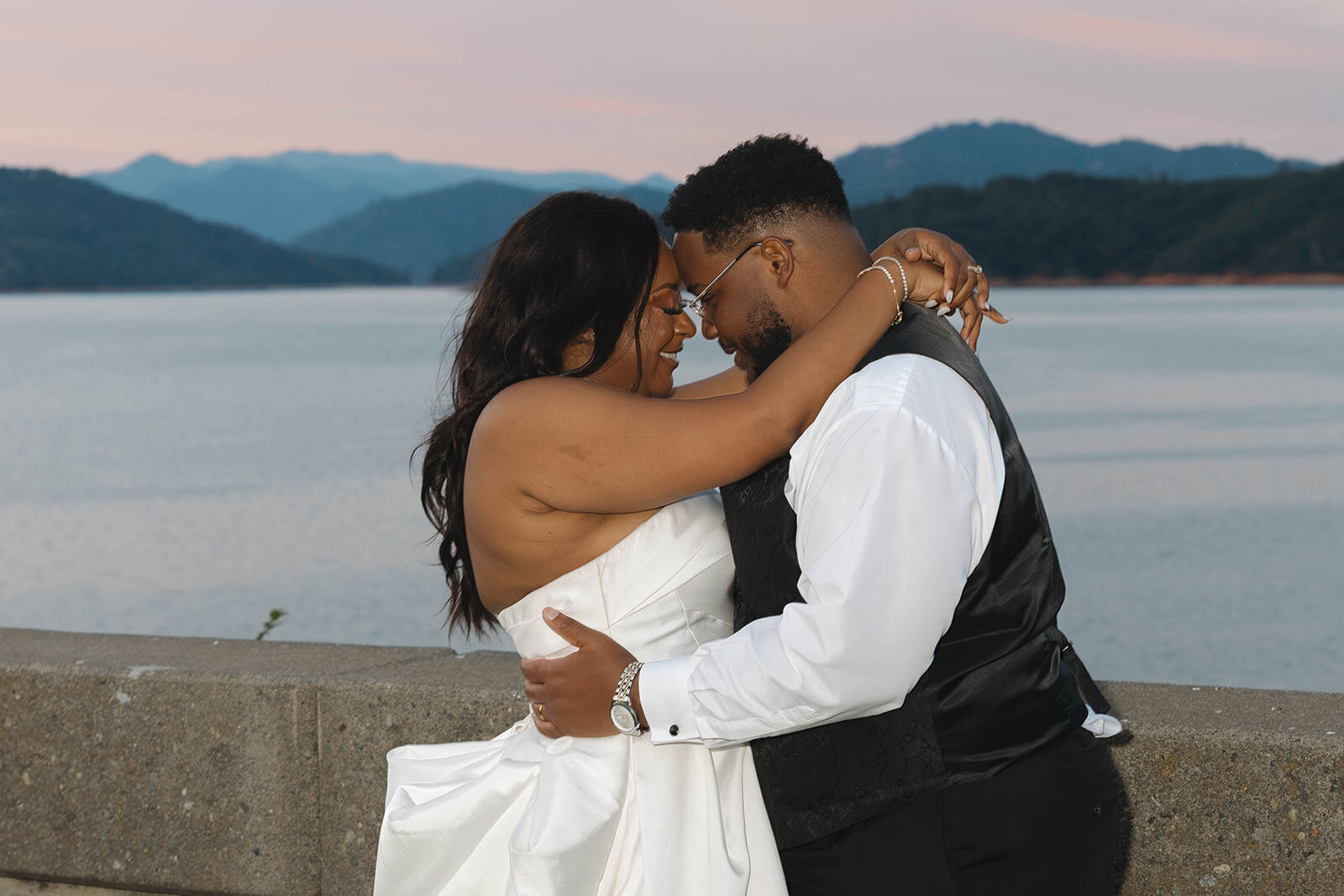 Bride and groom kissing at the lake at sunset