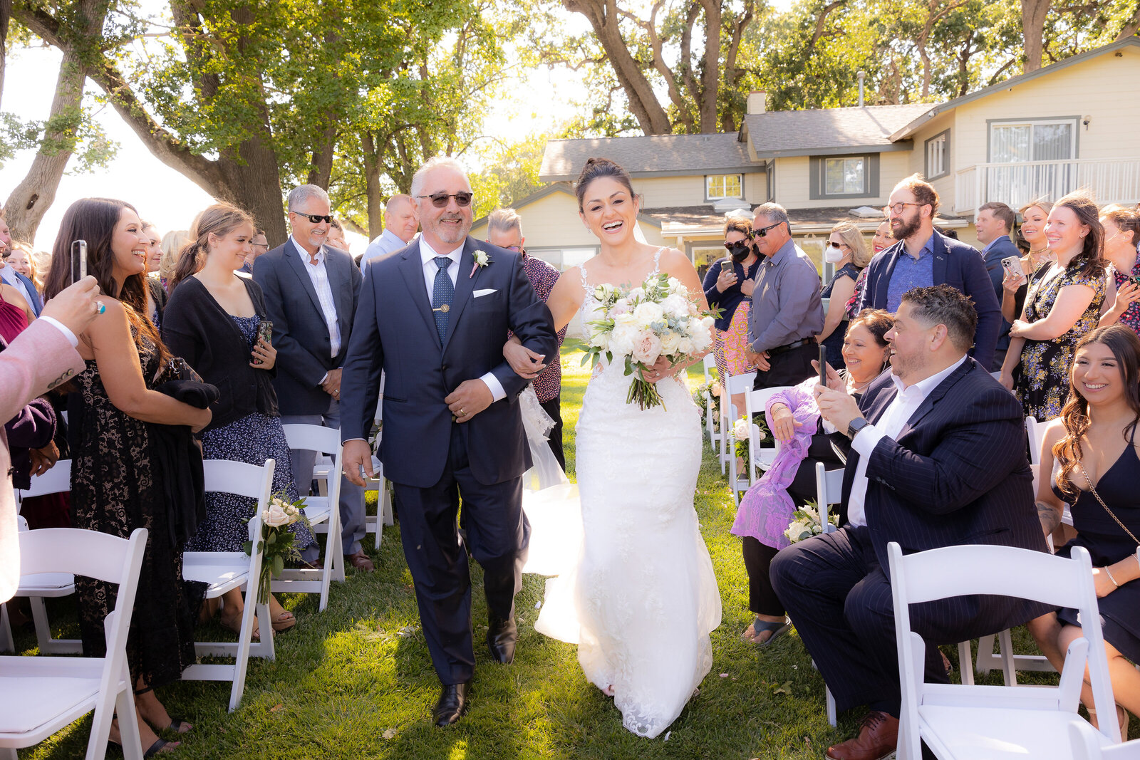 Philippe Studio Pro, Sacramento wedding photographer, captures bride walking down aisle with father during wedding ceremony with guests standing on both sides.