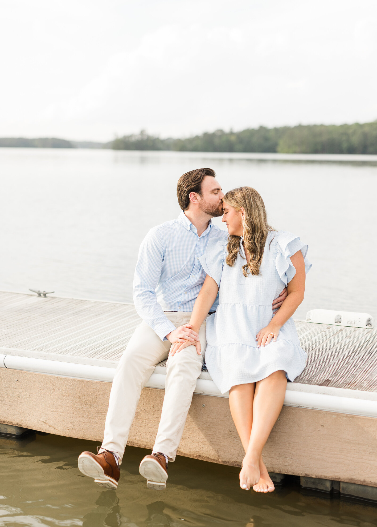 Julianna and Josh sharing a sweet kiss on a lakeside dock, photographed by Abby Bell Photography in Alabama.