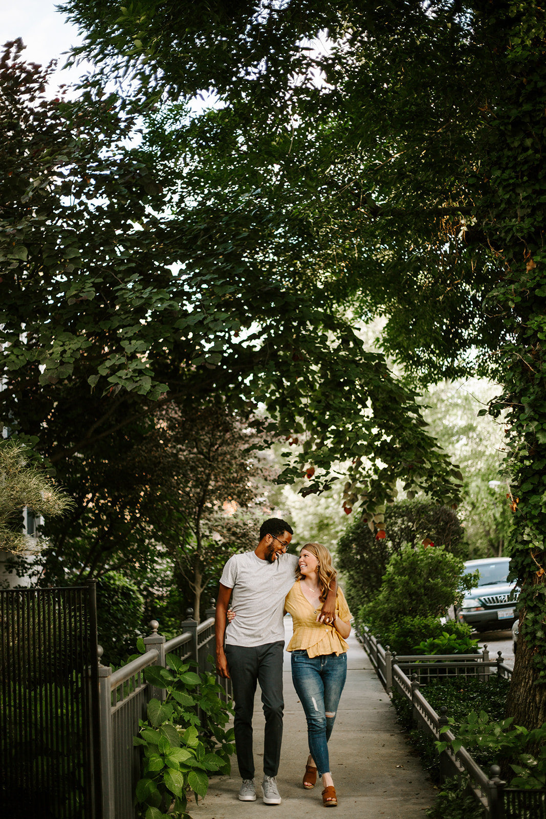 Couple walking with the guys arm around the girls shoulders walking down a path during their engagement session