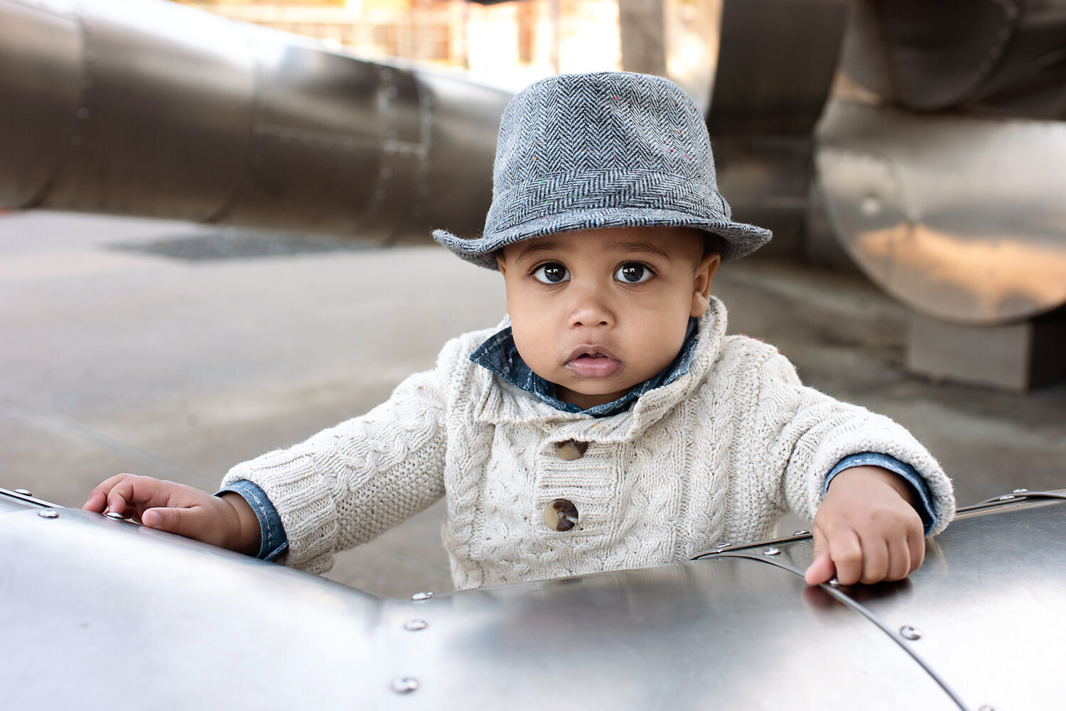 One year old boy wearing a hat and sweater at his one year old milestone photo shoot with Susan Baraban Photography.