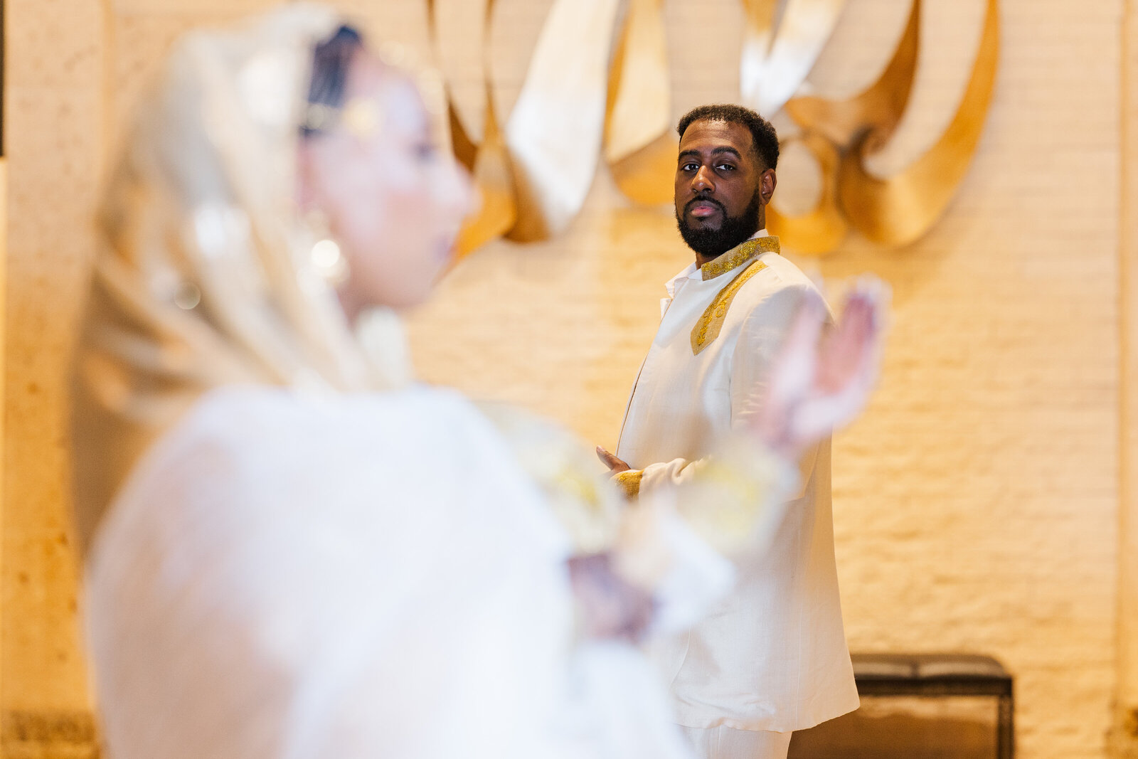 Bride-holding-wedding-ring-groom-in-the-back