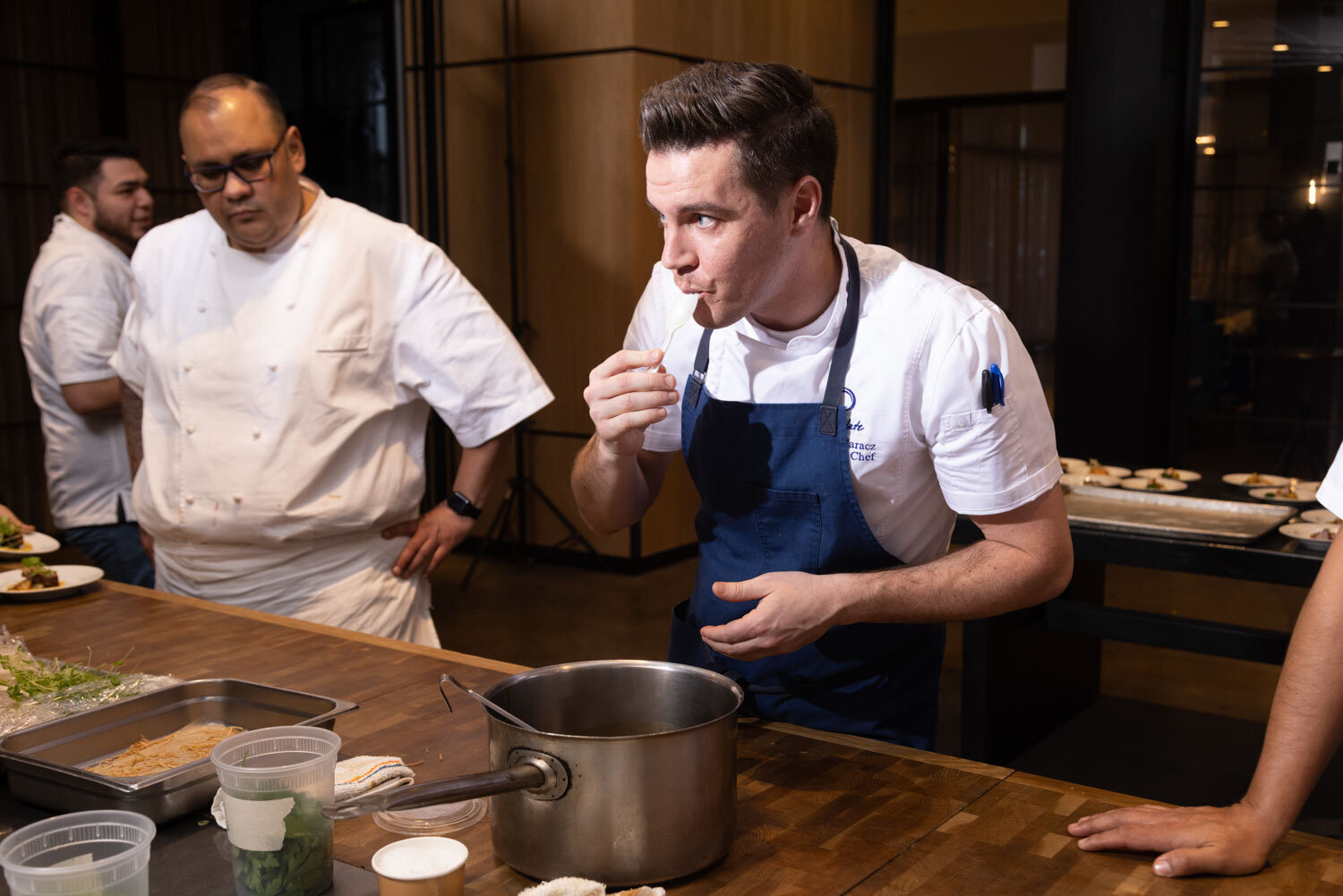 A man in an apron is eating out of a pot