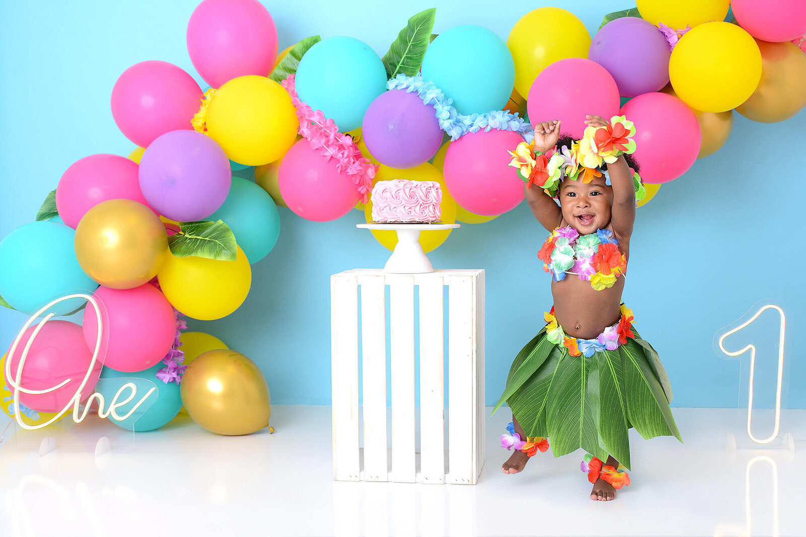 birthday girl wear a hawaiian outfit  and danced in front of a blue background with vibrant balloons