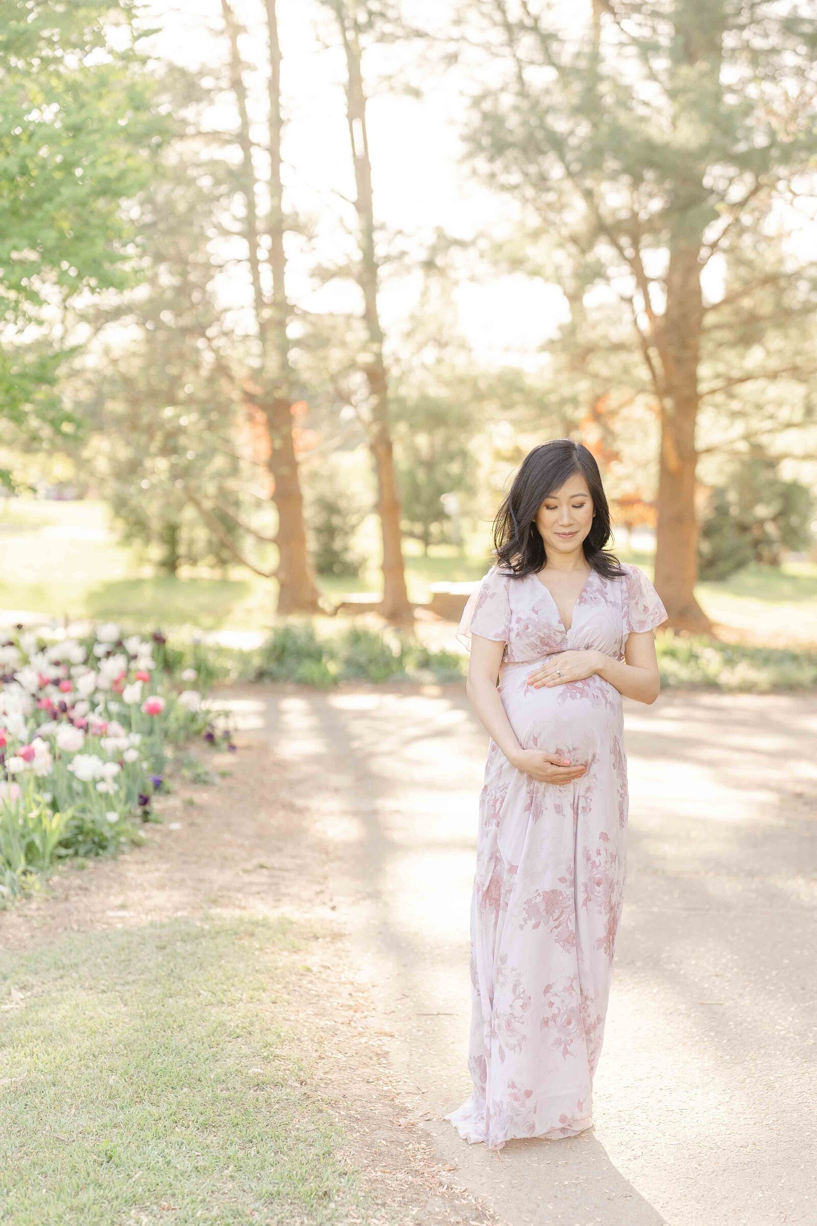 mom looking at belly during outdoor maternity picture in Ashburn, Virginia