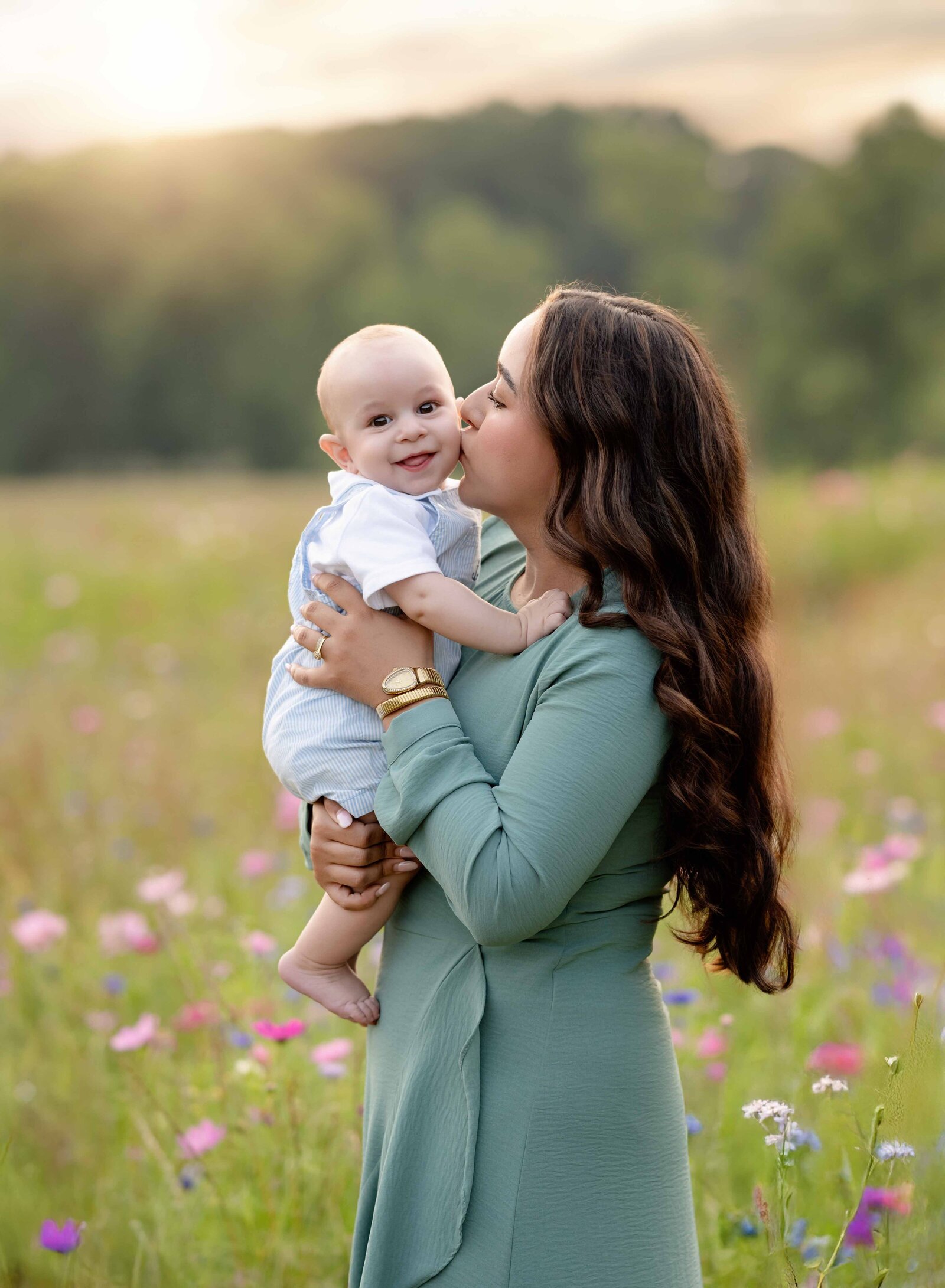 Mom kissing baby boy on cheek in a wildflower field. Mommy and me photo taken by Atlanta Photographer at prospect farms.