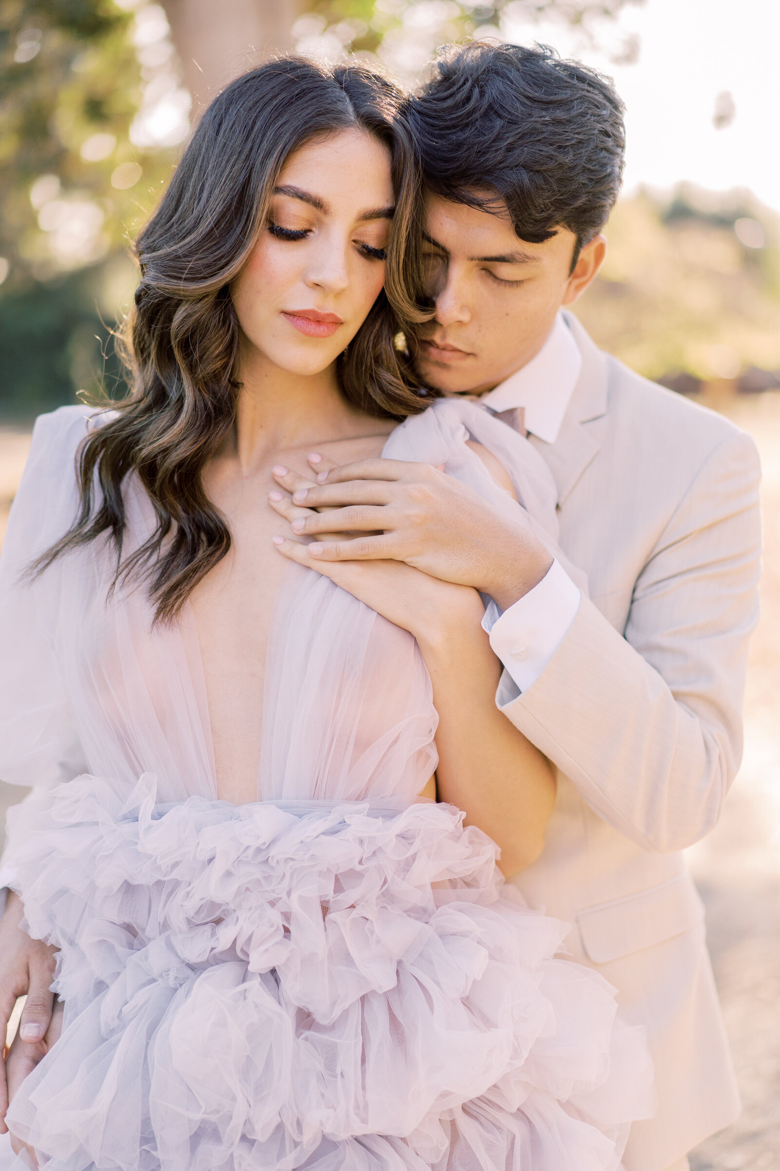 Portrait of a bride and groom in a lavender gown and cream suit embracing outdoors.