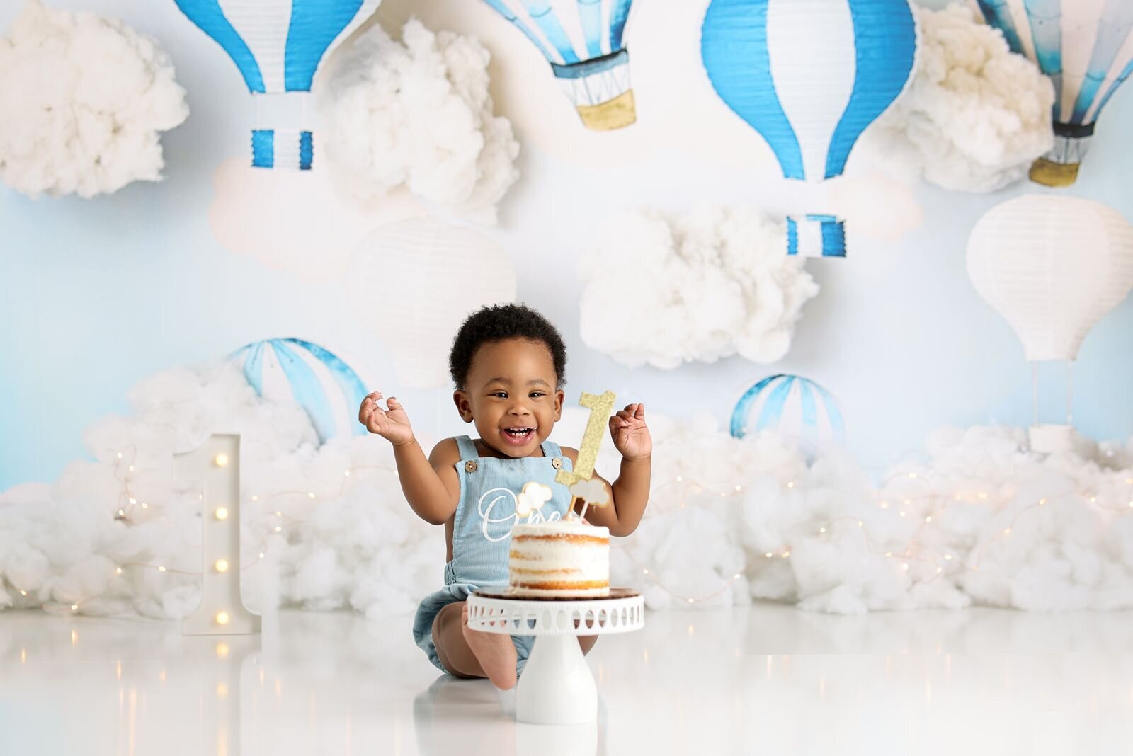 Baby enjoying a cake smash in a hot air balloon-themed setting