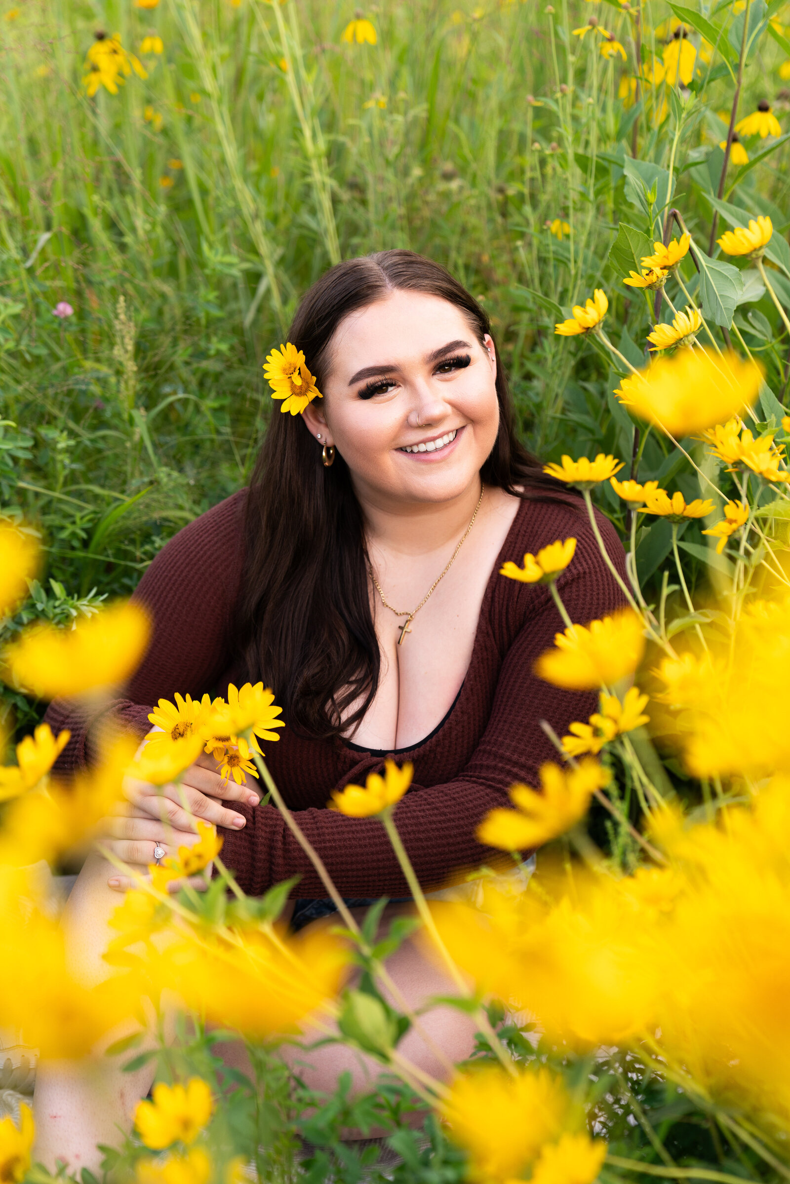 Teen girl sits in a wildflower field for her senior pictures at Whitetail Regional Woods in Farmington, Minnesota