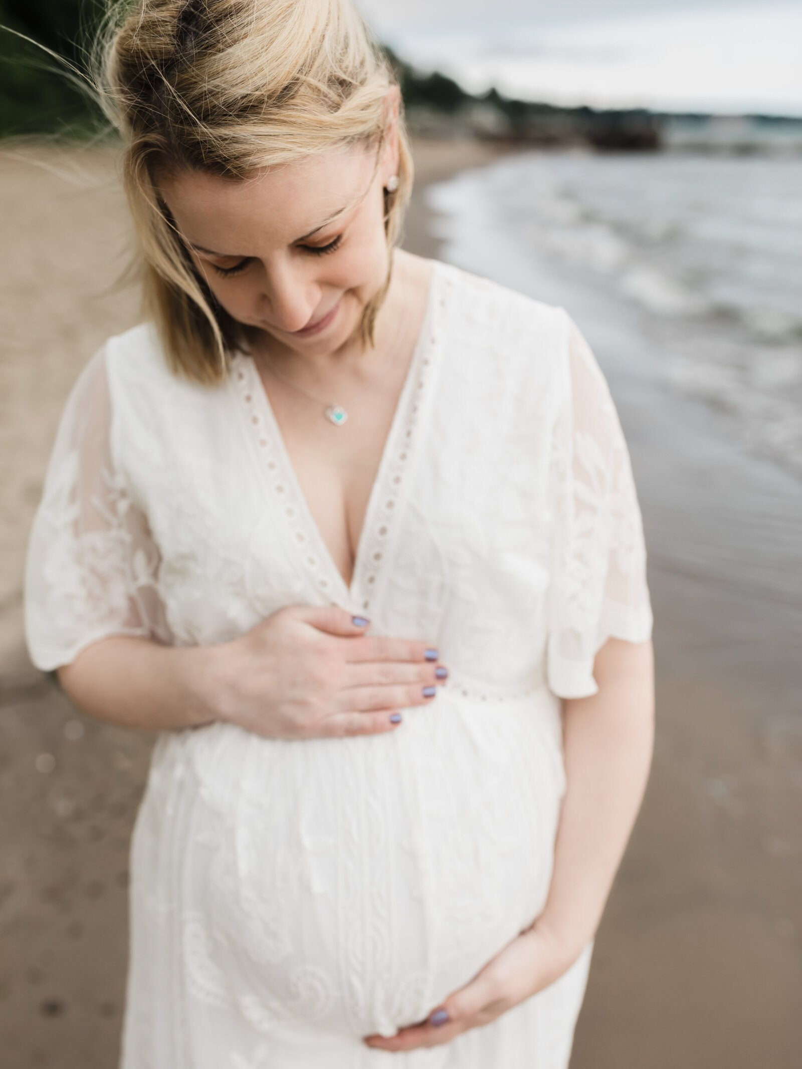 pregnant mother in white lace maternity gown for photoshoot on the beach