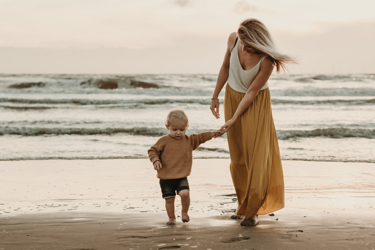 moeder en zoon aan de hand  op het strand