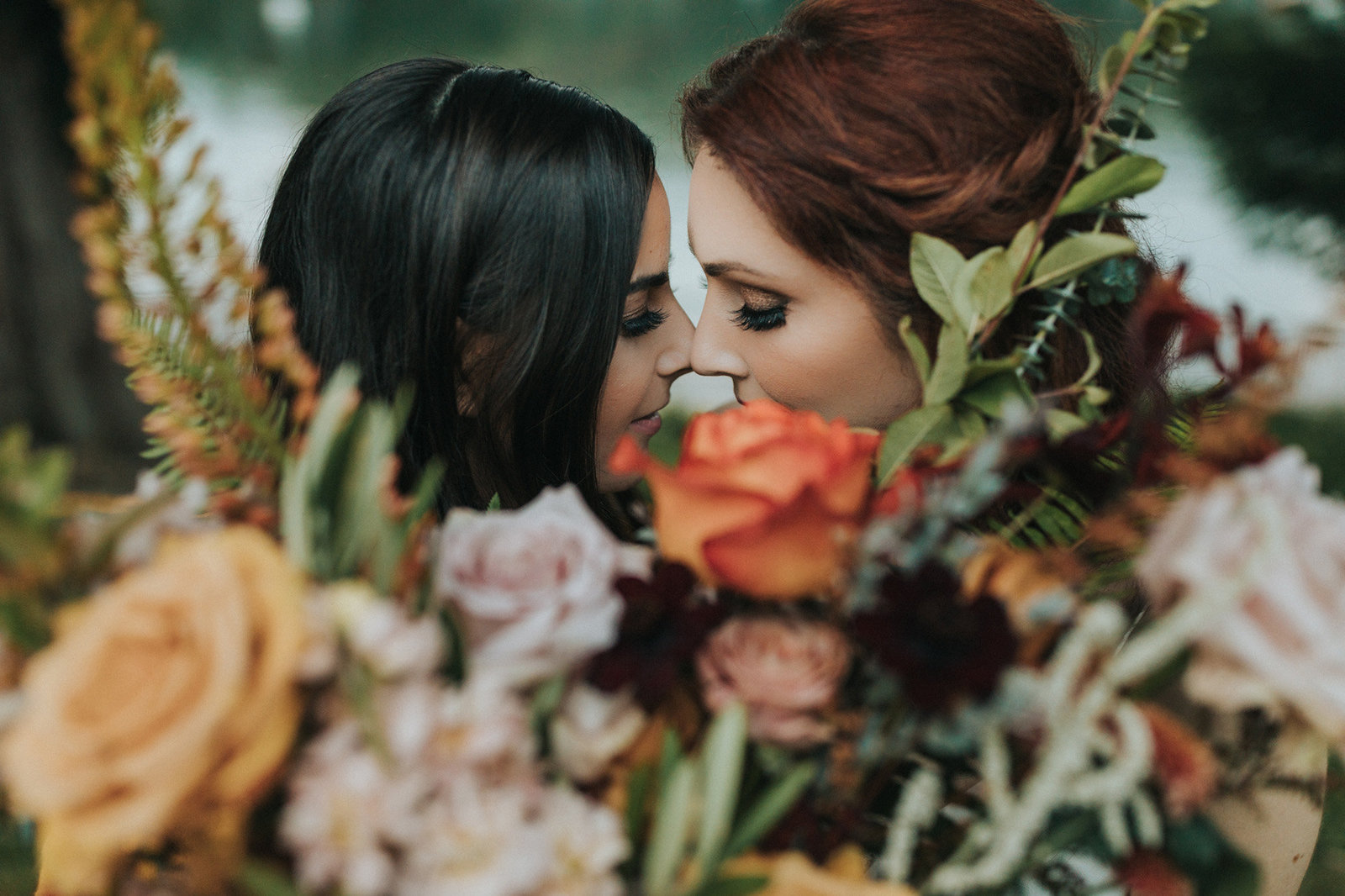 Two brides embracing behind bouquet