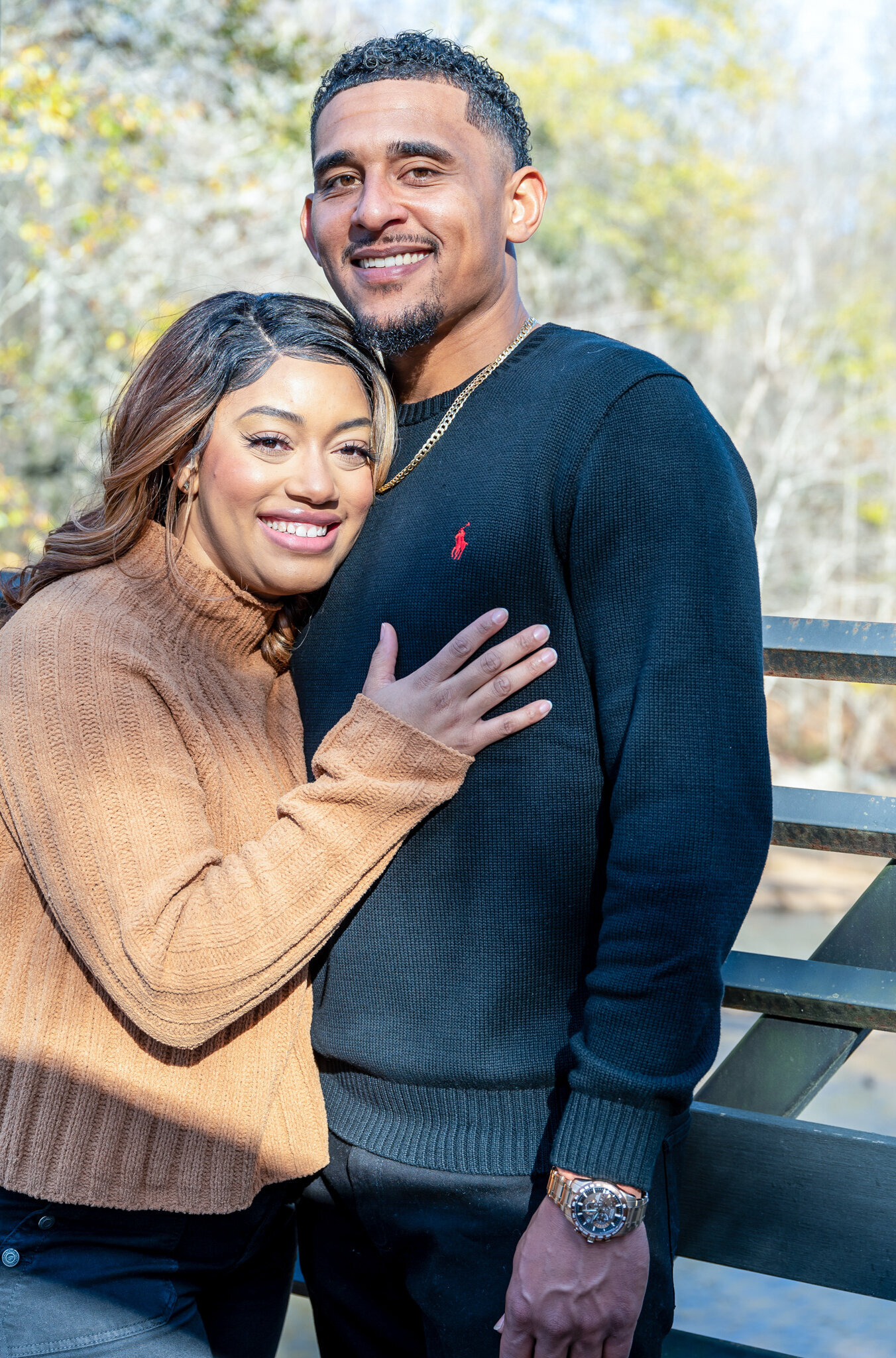 a woman holding onto a man both are smiling at the camera photographed by Millz Photography in Greenville, SC