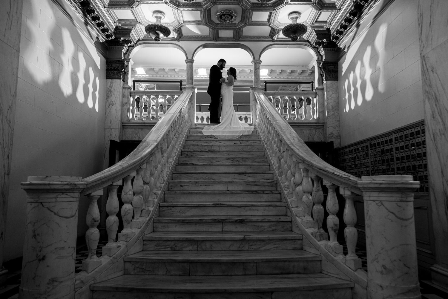 A bride and groom are kissing on a set of stairs.
