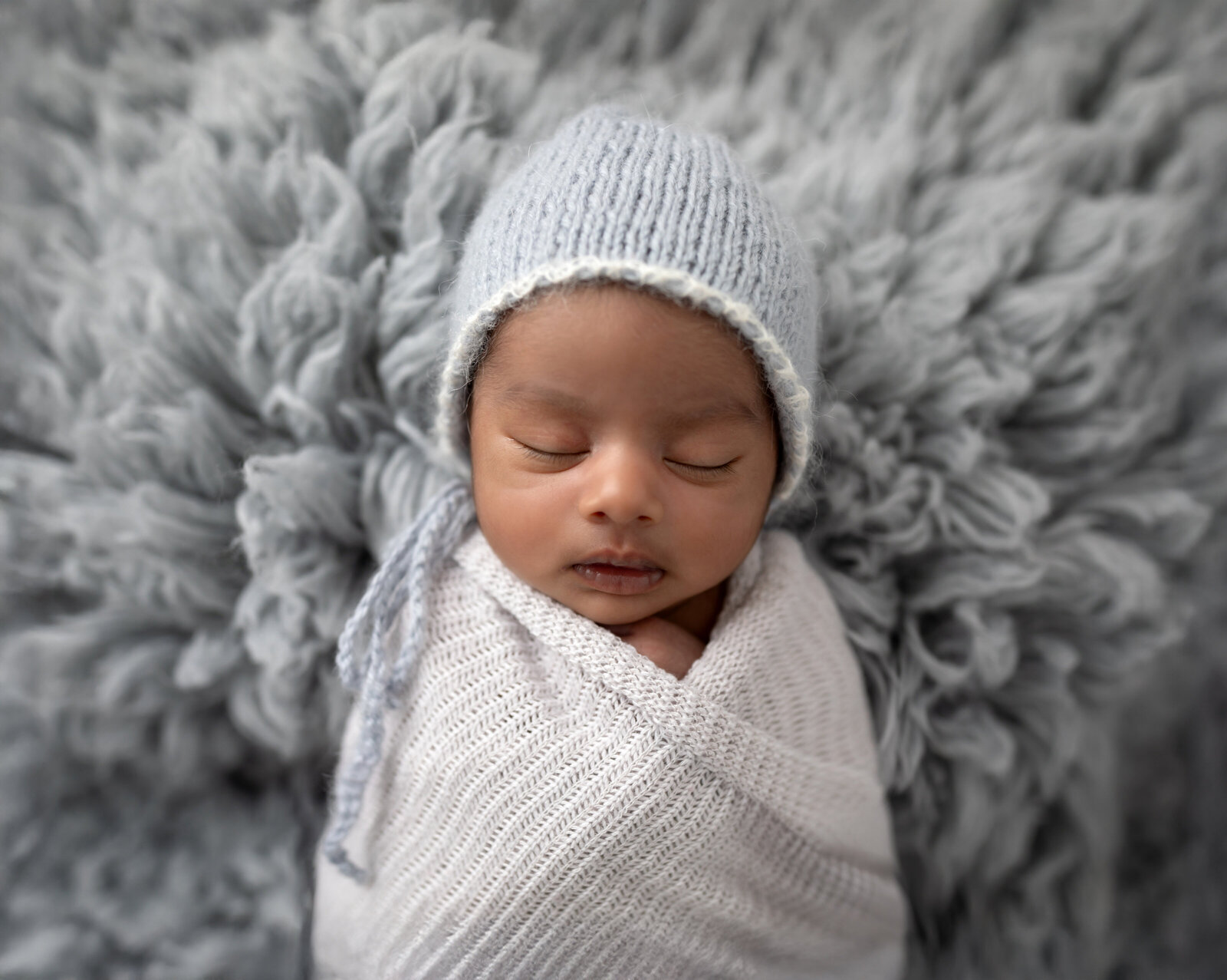 newborn baby girl swaddled in gray wrap for studio newborn portraits