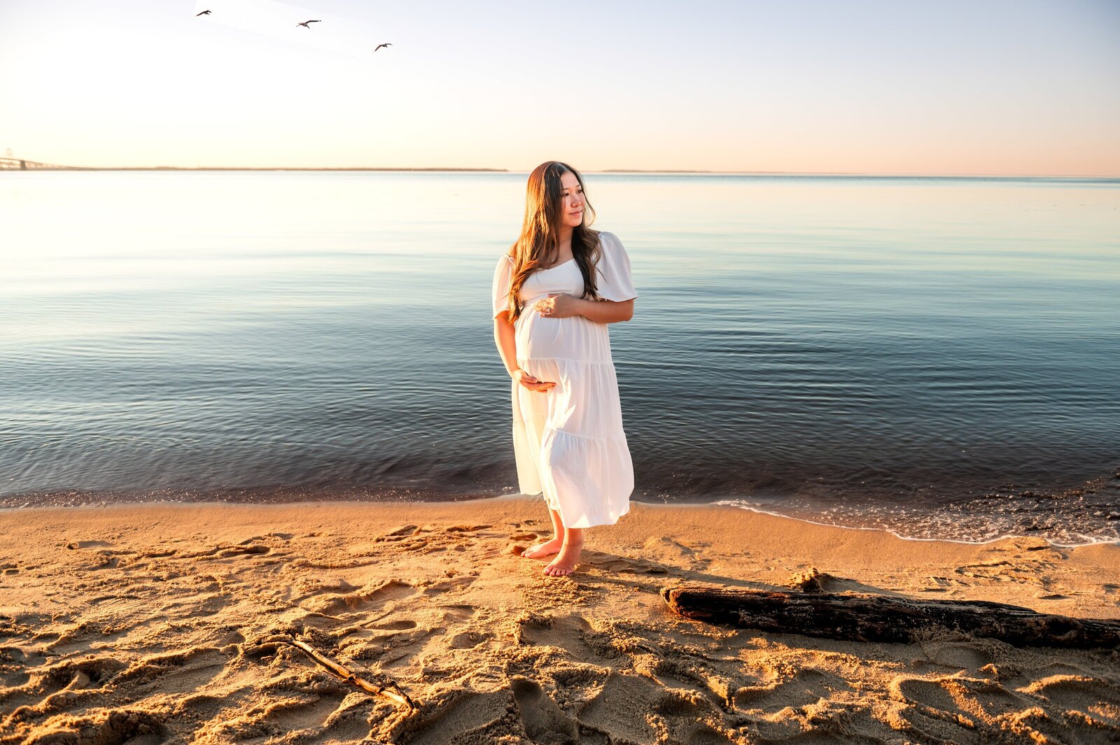 woman holding her pregnant belly looking over the bay water