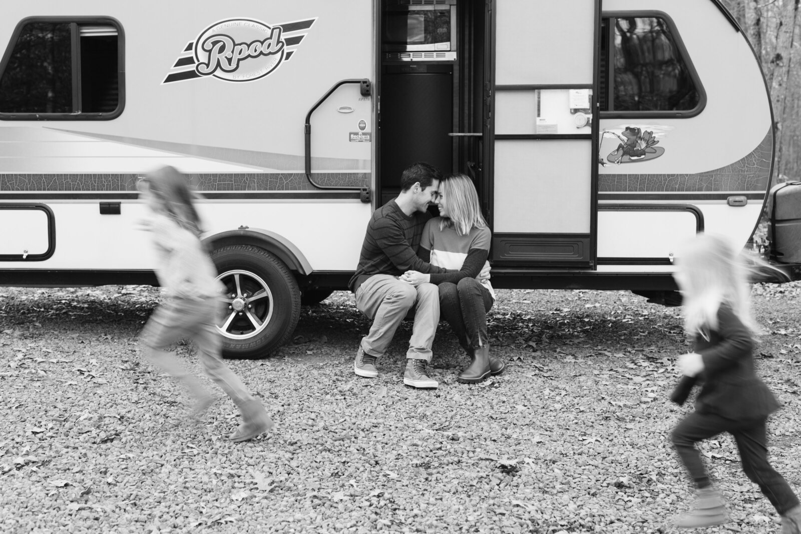 Parents sitting on steps of RV as two children run past - DC Family Photographer
