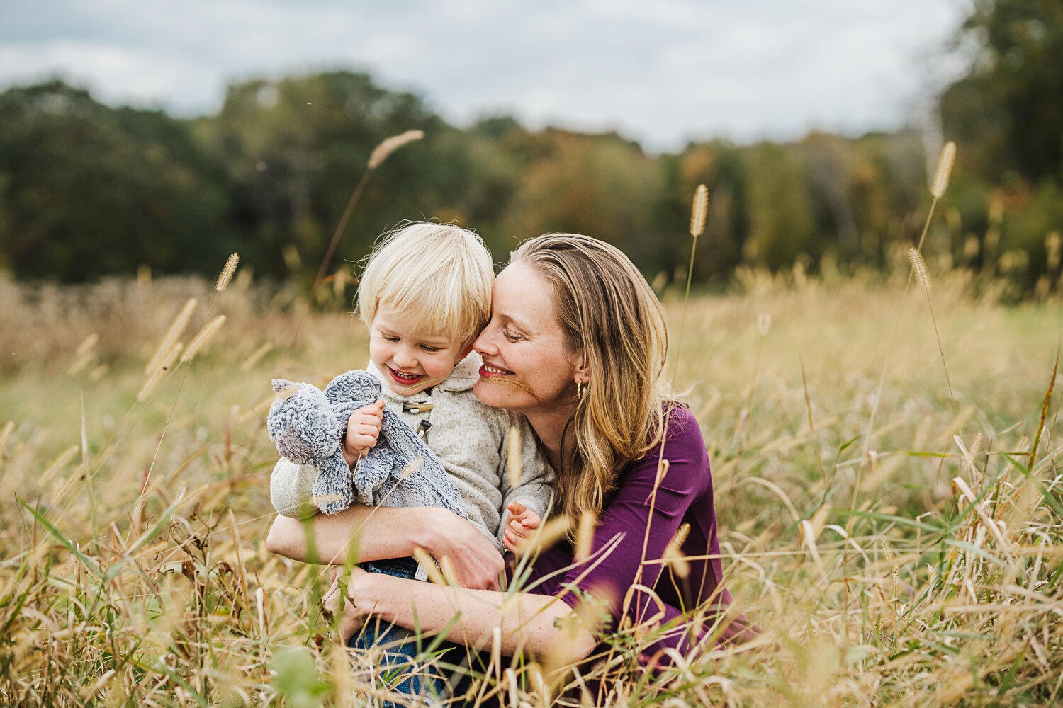 mom snuggles toddler boy in a wheat field