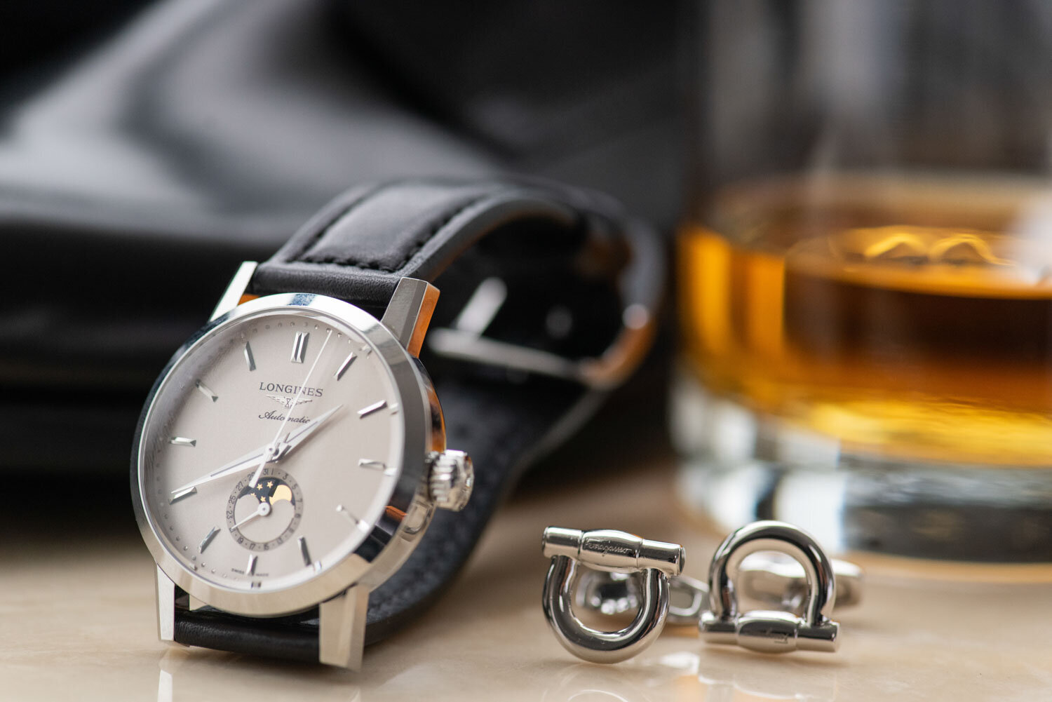 A longines watch sits next to a pair of cufflinks