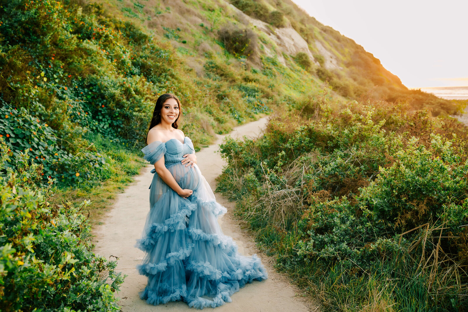 Expectant Momma holding bump in blue ruffled dress in Los Angeles, CA by Ashley Nicole Photography.