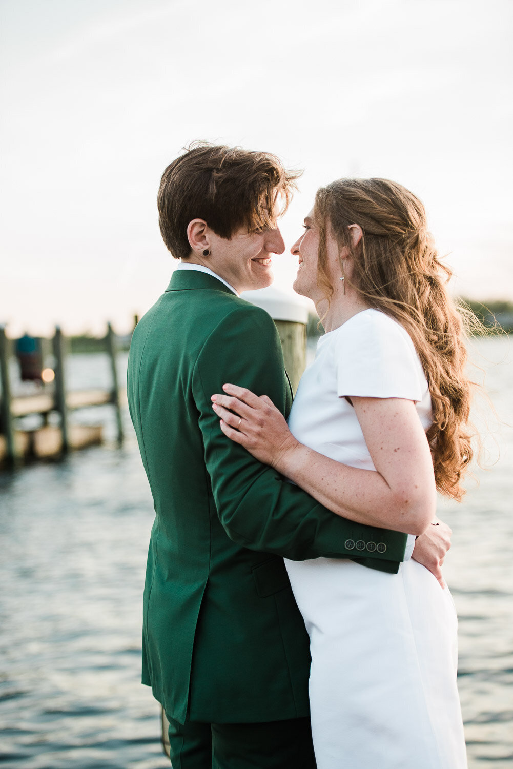 brides embrace and smile on dock