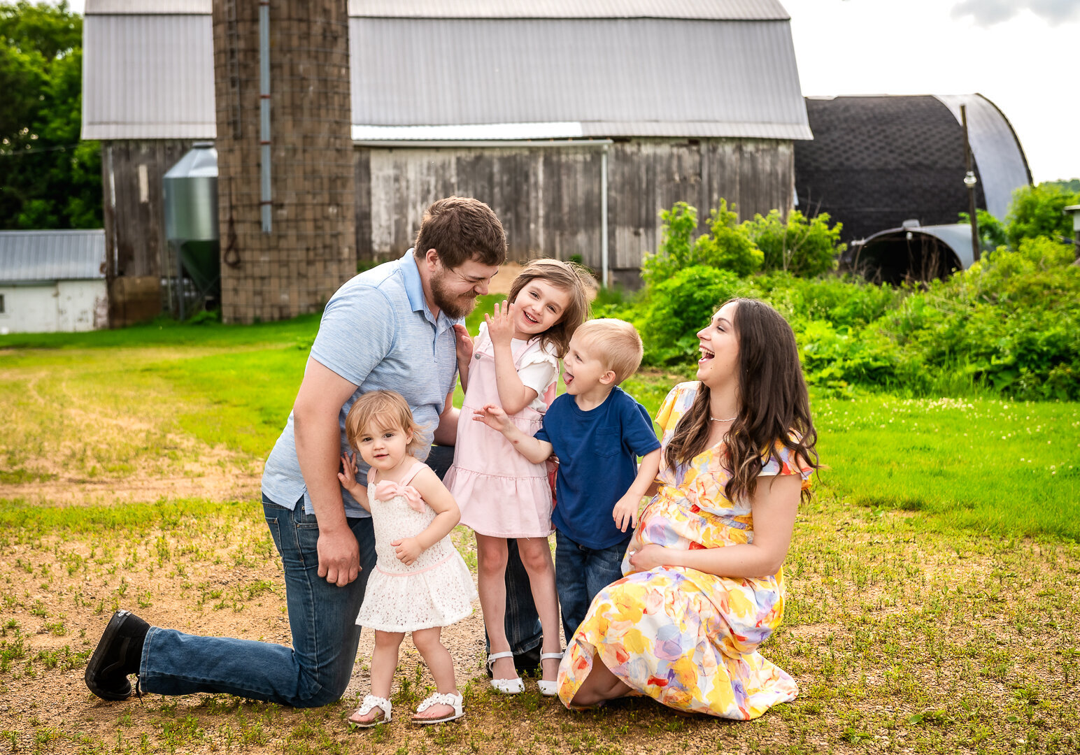 Pregnant mother smiling with her partner and child during outdoor maternity family photo session in Emerald, WI.