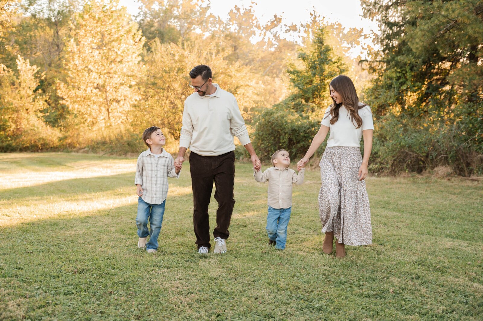 Family holding hands and walking along the water during a Baltimore family photographer sunset session.