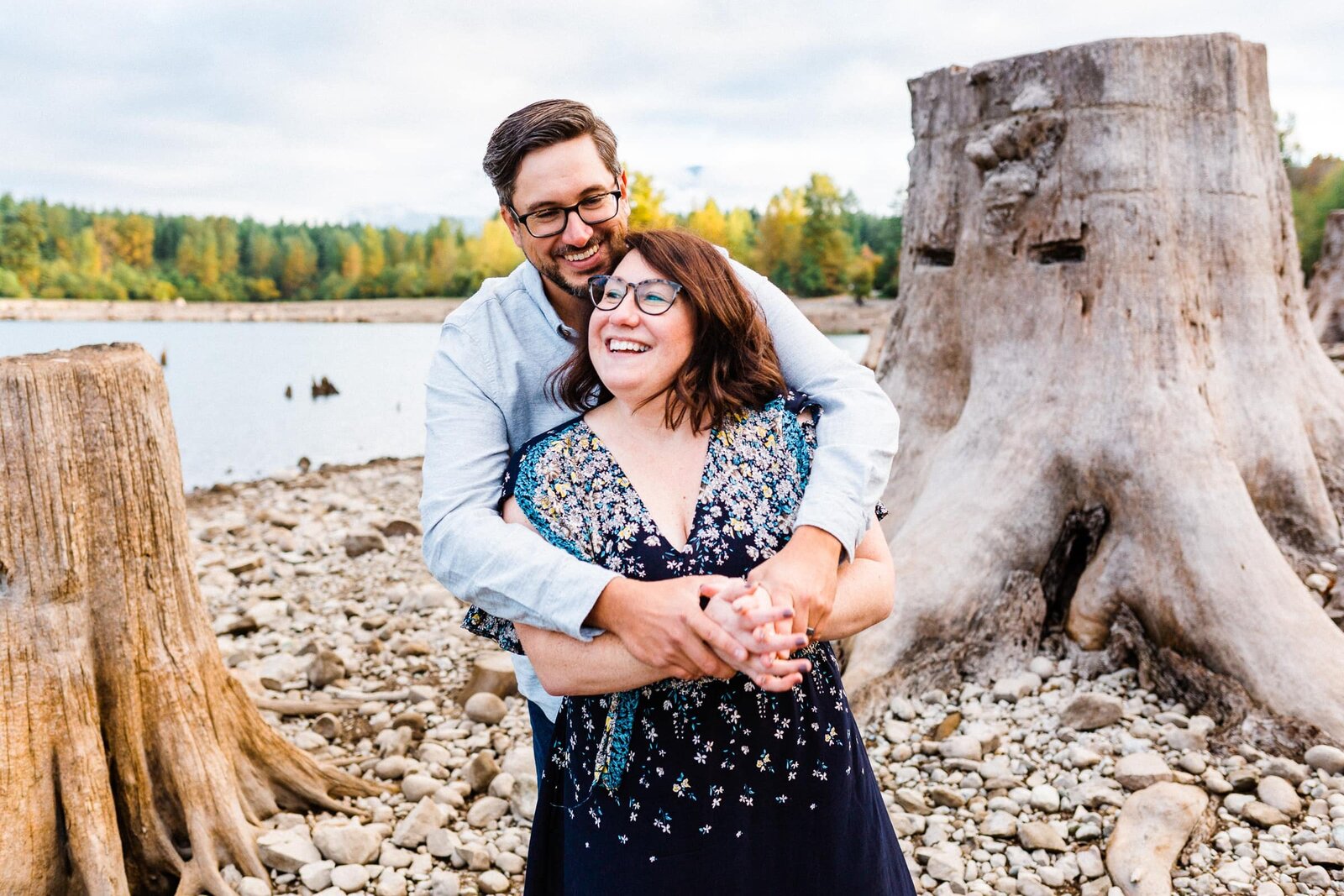 couple cuddling and laughing among tree stumps