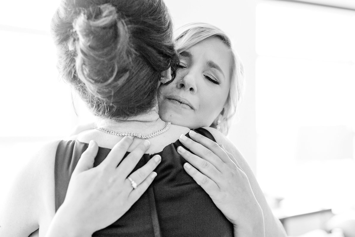 Emotional bride hugs mom.