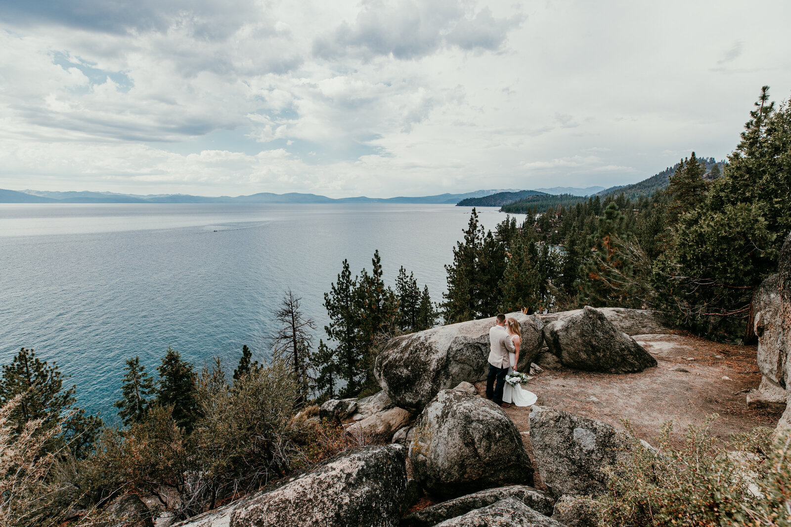 Couple standing on a rocky overlook above Lake Tahoe during their elopement — photographed by Kristin Smith, Lake Tahoe elopement photographer.