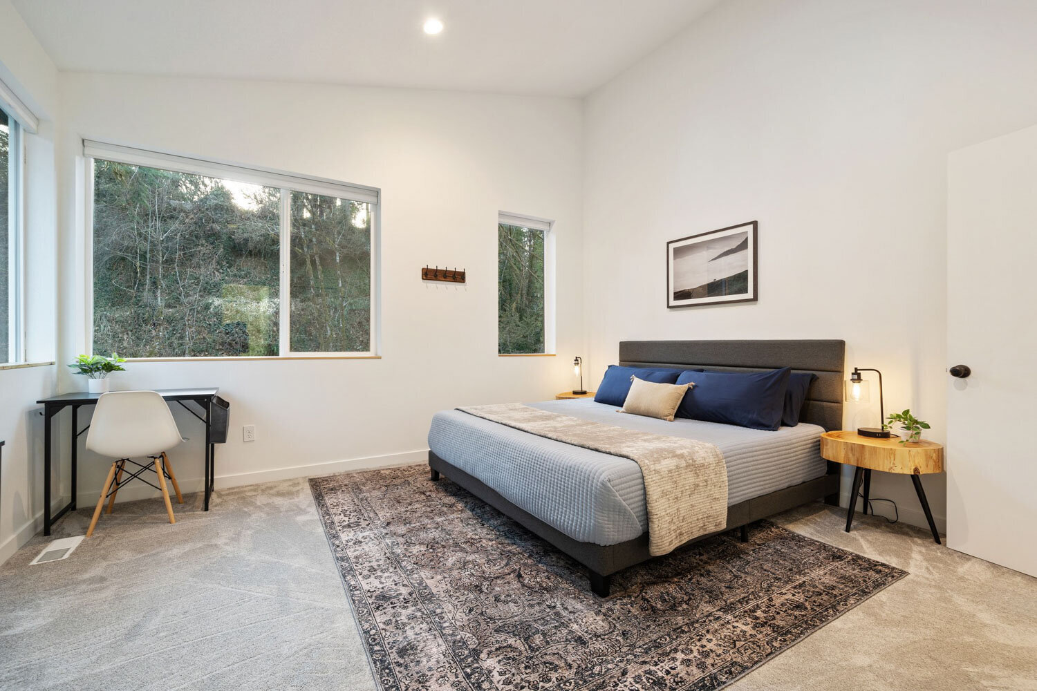 A cozy modern bedroom with a grey upholstered bed and wooden side tables