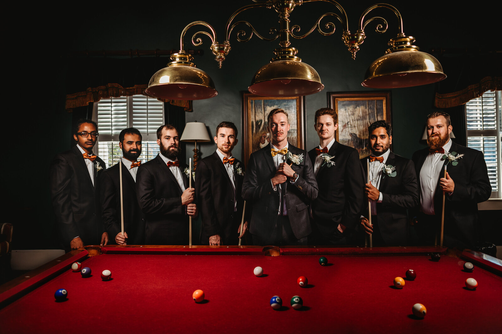 Baltimore photographers captures groomsmen photo with groom and his groomsmen standing around a pool table in a lodge